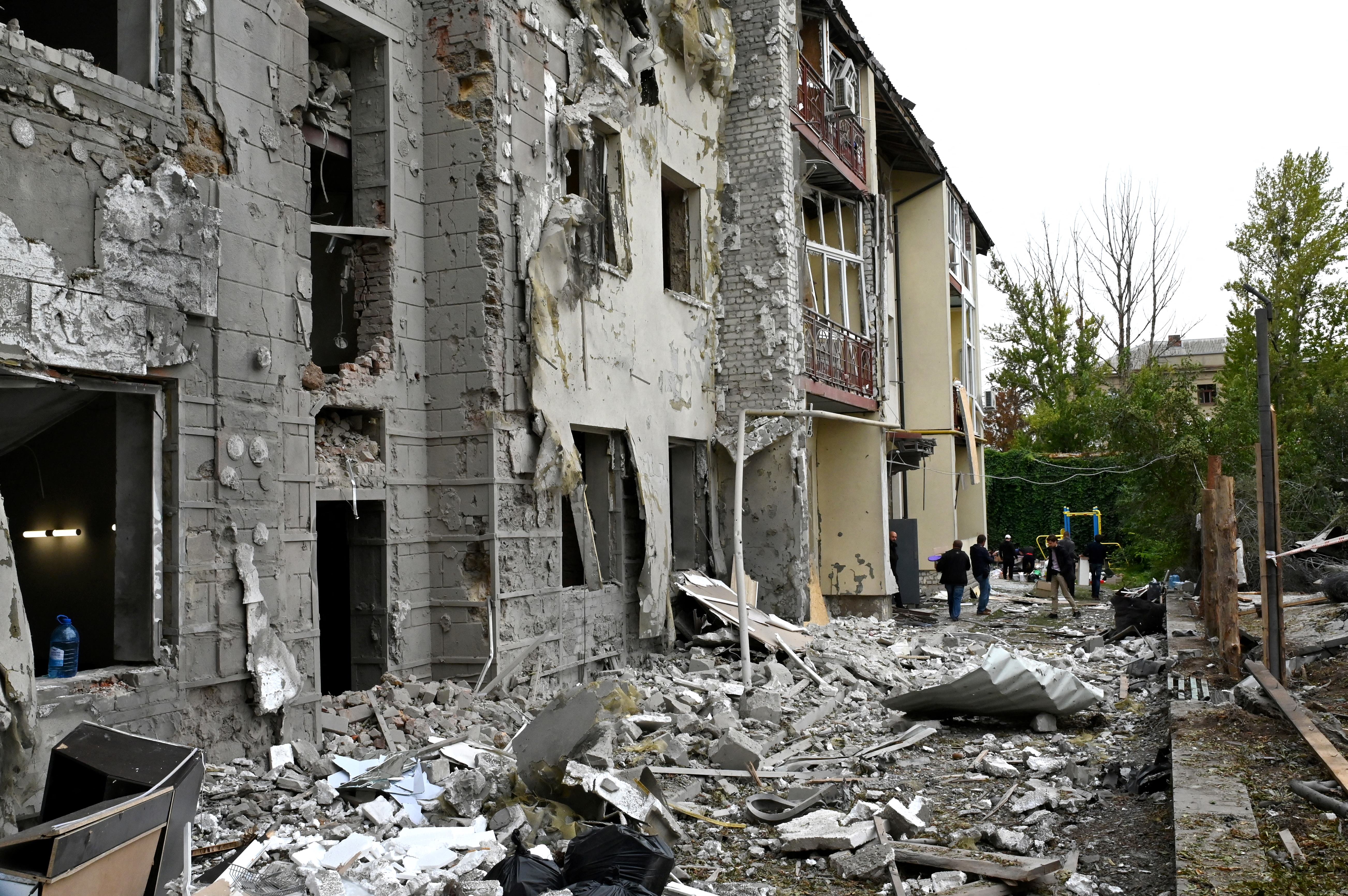 Local residents stand outside their building partially destroyed by a missile strike on Kharkiv on September 12, 2022 amid the Russian invasion of Ukraine. (Photo by SERGEY BOBOK / AFP)