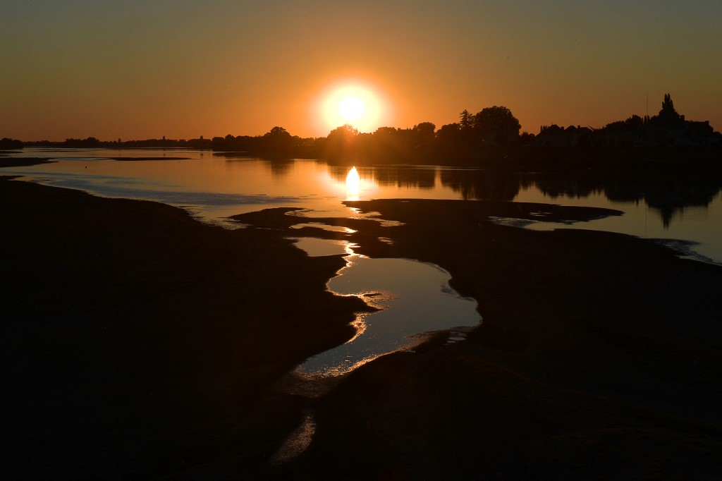 This picture taken on August 7, 2022, shows sandbanks and the low levels of the Loire river at sunset in Saint-Mathurin-sur-Loire, western France. - France is experiencing a drought exacerbated by a third extreme heatwave of the summer. (Photo by Jean-Fran�ois MONIER / AFP)