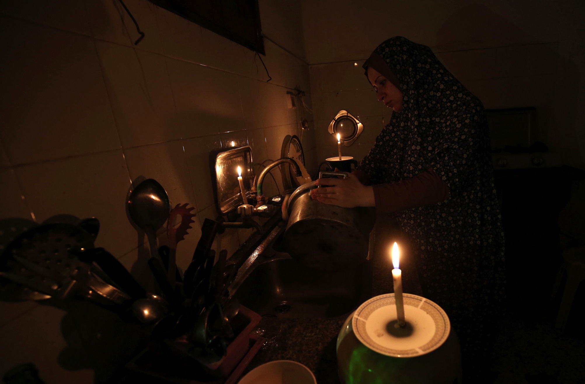 A la luz de las velas, una plaestina lava platos en en el campamento de desplazados en Rafah, en el sur de la franja de Gaza.