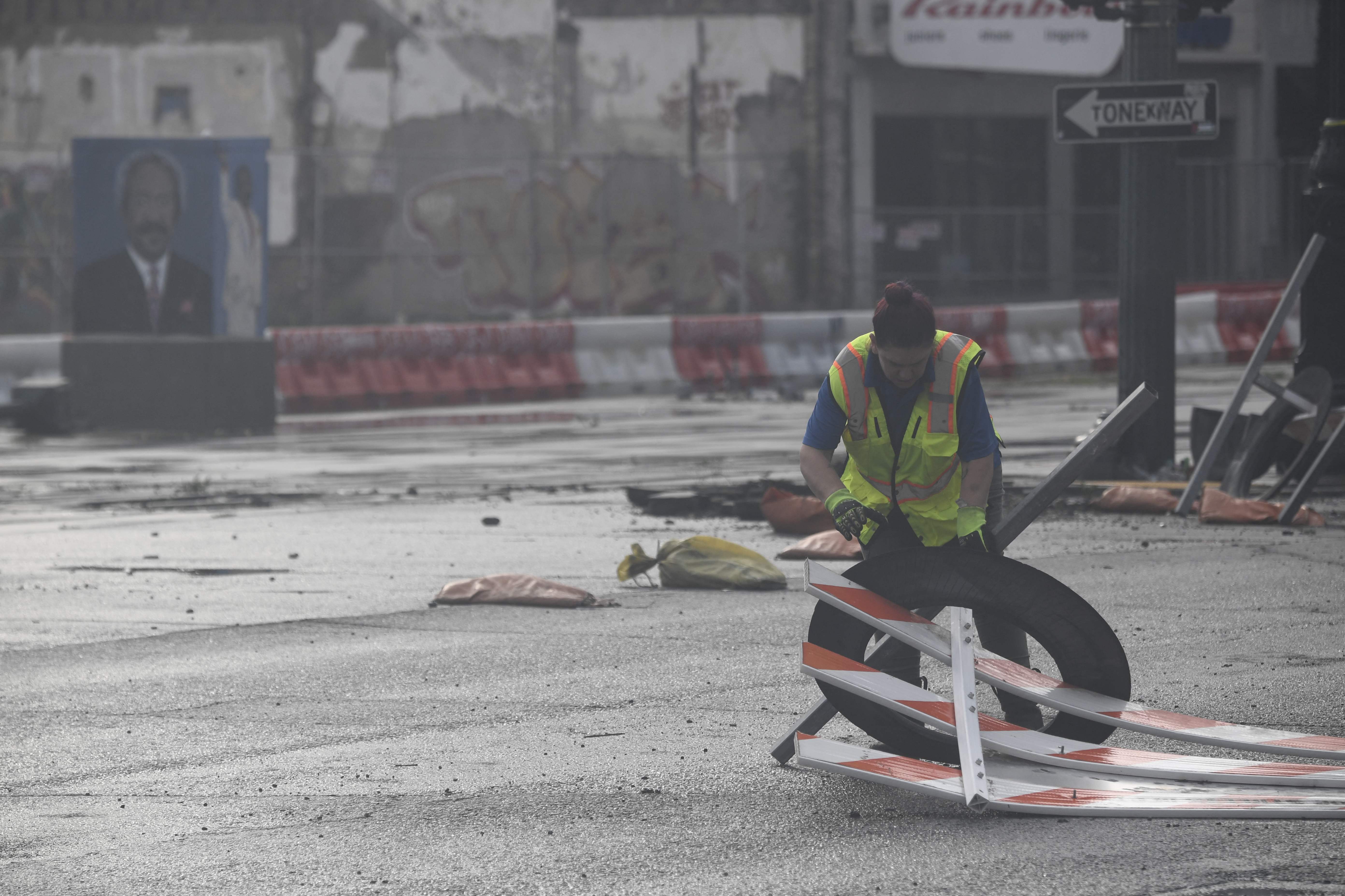 A worker removes barriers on the road that were blown over by the wind on Canal Street in New Orleans, Louisiana, on August 30, 2021 after Hurricane Ida made landfall. - Powerful Hurricane Ida battered the southern US state of Louisiana, leaving at least one dead and knocking out power for more than a million people, including the whole of New Orleans. Ida slammed into the Louisiana coast as a Category 4 storm on August 29, 2021, 16 years to the day after Hurricane Katrina devastated New Orleans, but had weakened to a tropical storm early August 30, 2021.The storm knocked out power for all of New Orleans, with more than a million customers across Louisiana without power, according to outage tracker PowerOutage.US. (Photo by Patrick T. FALLON / AFP)