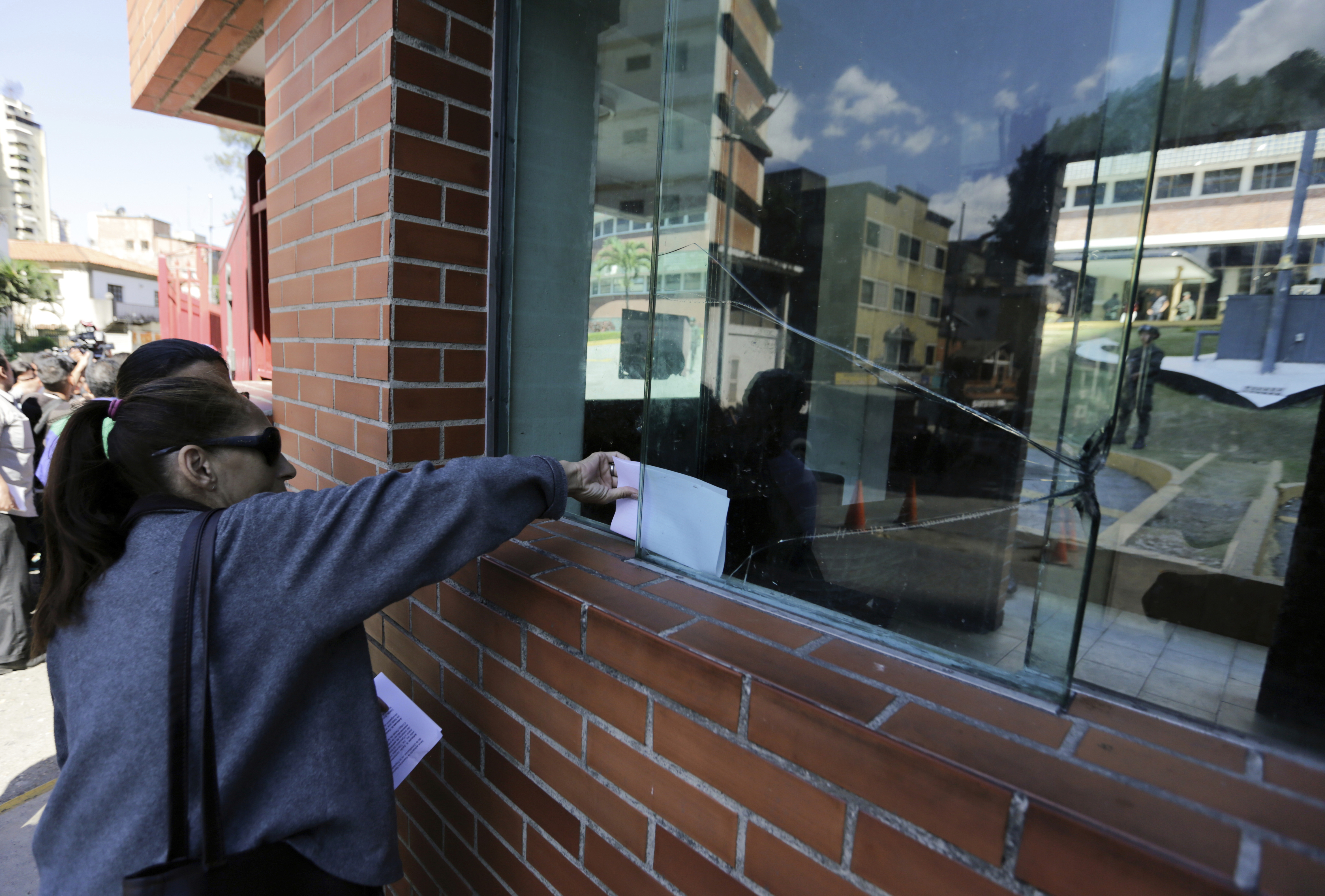 An opposition member leaves a copy of a proposed amnesty law at a main entrance of Venezuela's Navy headquarters in Caracas, Venezuela, Sunday, Jan. 27, 2019. The opposition is attempting to pressure the armed forces to withdraw their support of President Nicolas Maduro and back self-declared interim leader Juan Guaido. (AP Photo/Fernando Llano)