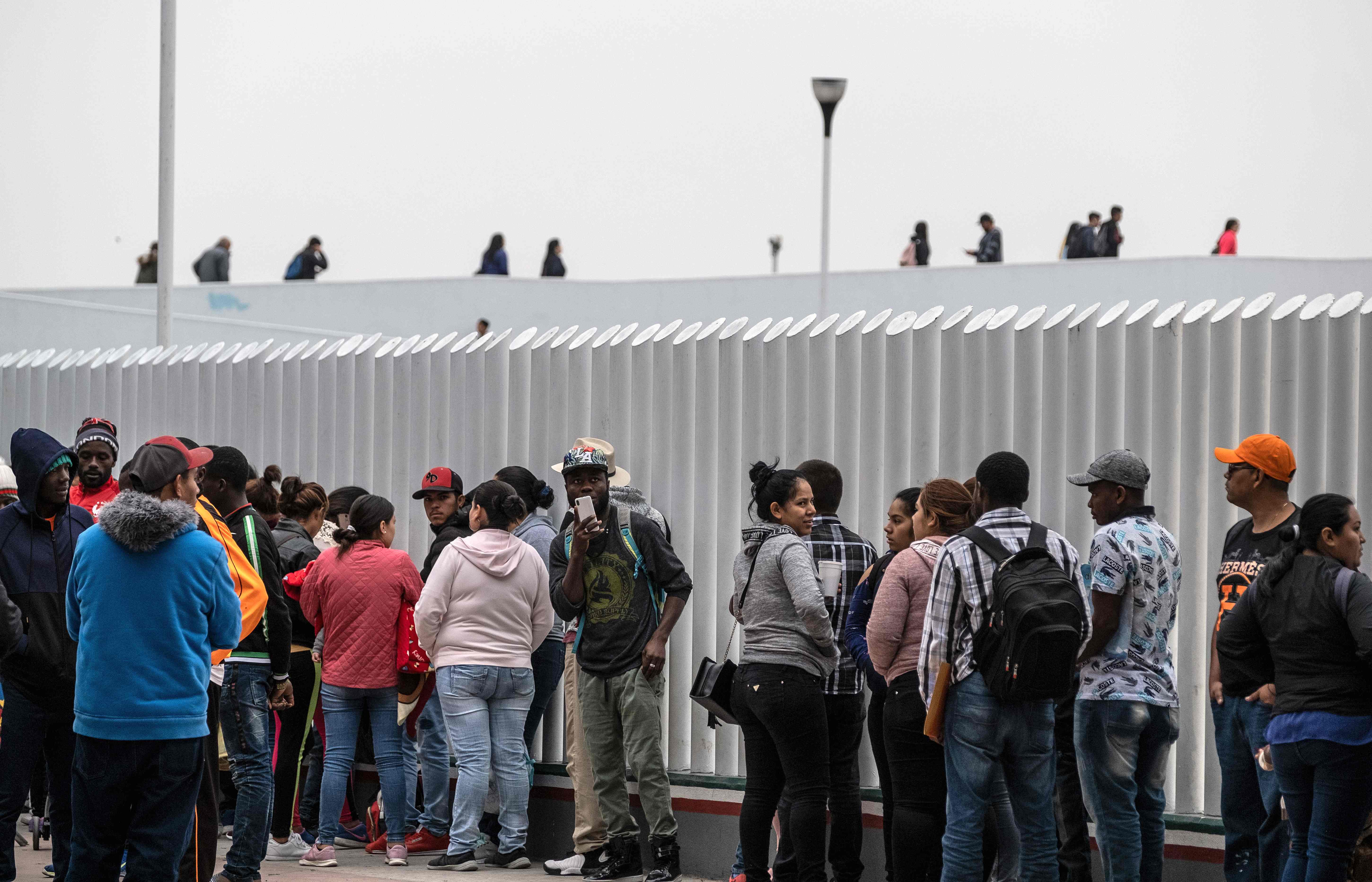 Asylum seekers queue for a turn for an asylum appointment with US authorities, at the US-Mexico El Chaparral crossing port in Tijuana, Baja California State, Mexico, on May 31, 2019. - Washington will impose a five percent tariff on all goods from Mexico starting on June 10, a measure that will last until "illegal migrants" stop coming through the country into the US, President Donald Trump said Thursday. (Photo by Guillermo Arias / AFP)