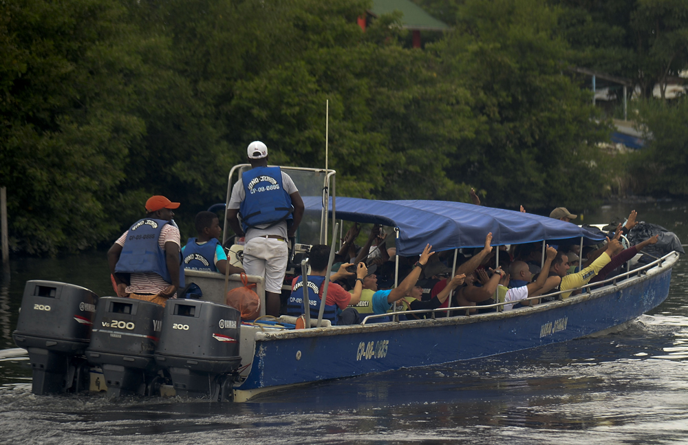 Migrantes cubanos y haitianos abordan un bote hacia Capurgana, en el golfo caribeño de Uraba (noroeste de Colombia) para entrar ilegalmente a Panamá a través de la selva, este sábado 6 de agosto. | AFP