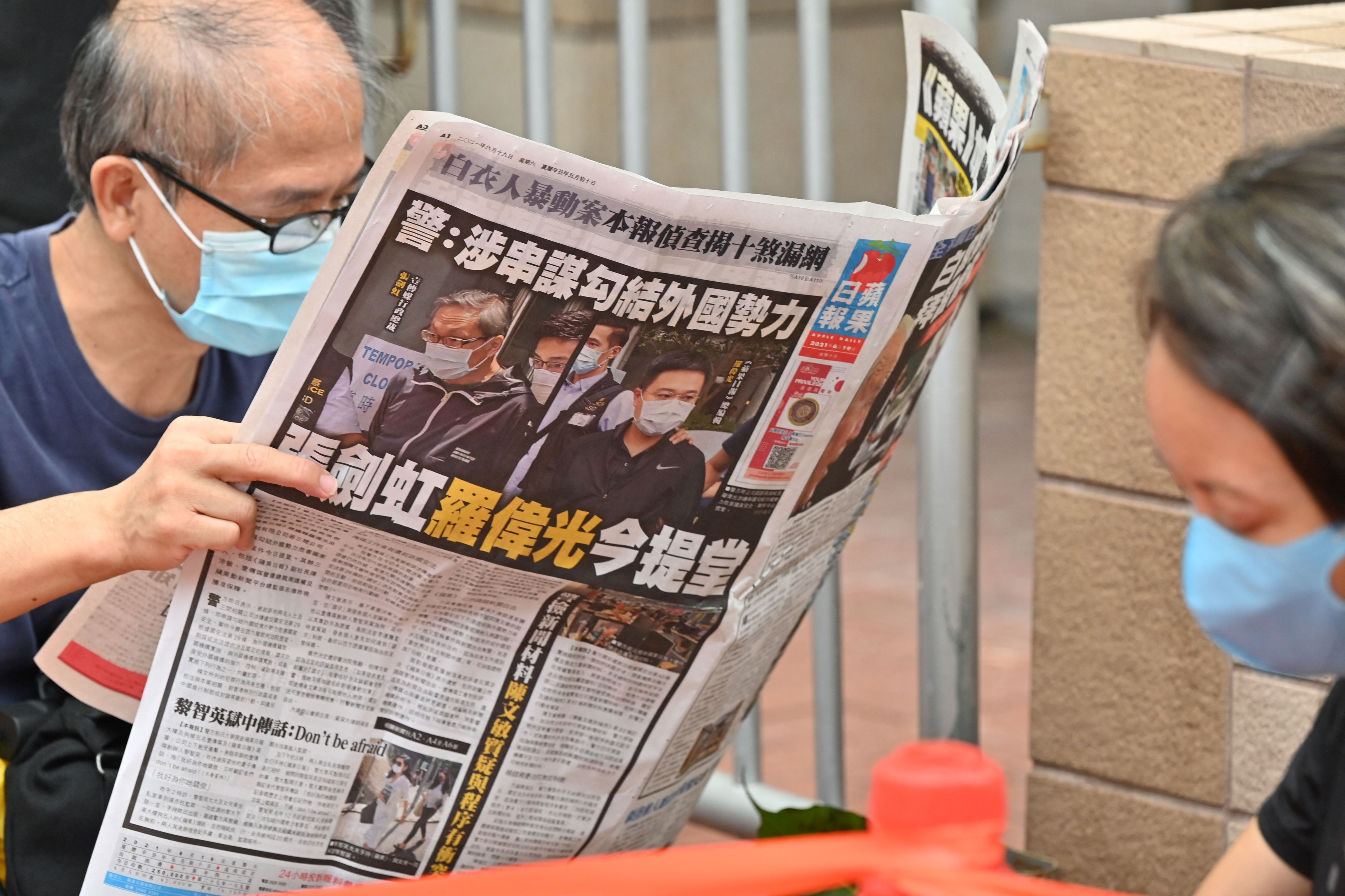 A supporter of two executives from Hong Kong's pro-democracy Apple Daily newspaper, chief editor Ryan Law and CEO Cheung Kim-hung, reads a copy of the newspaper outside court in Hong Kong on June 19, 2021, after the two were charged with collusion over their newspaper's coverage after authorities deployed a sweeping security law. (Photo by Peter PARKS / AFP)