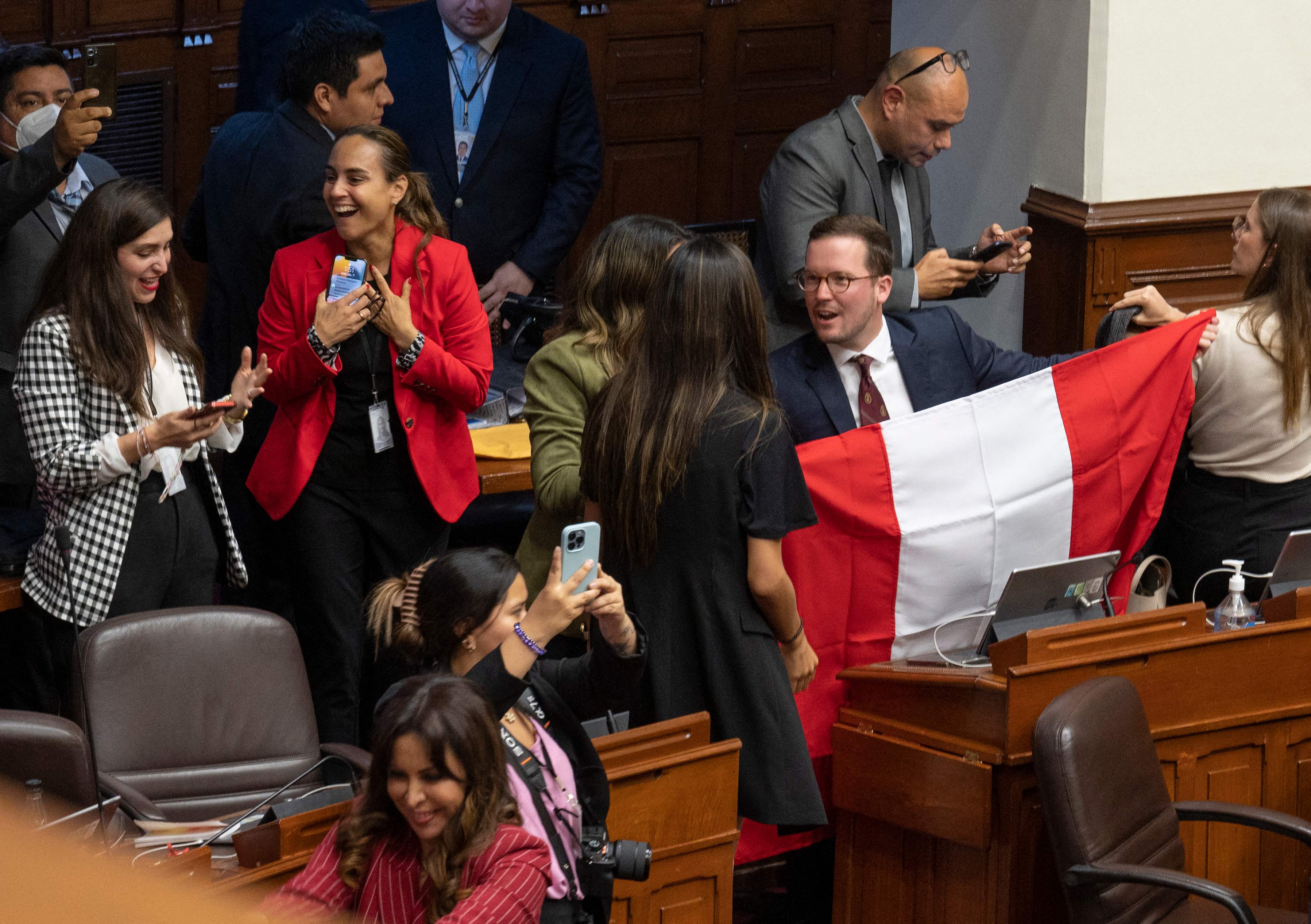 Peruvian congress members react after the vote for the impeachment of President Pedro Castillo in Lima on December 7, 2022. - Peru's President Pedro Castillo dissolved Congress on December 7, 2022, announced a curfew and said he will form an emergency government that will rule by decree, just hours before the legislature was due to debate a motion of impeachment against him. (Photo by Cris BOURONCLE / AFP)