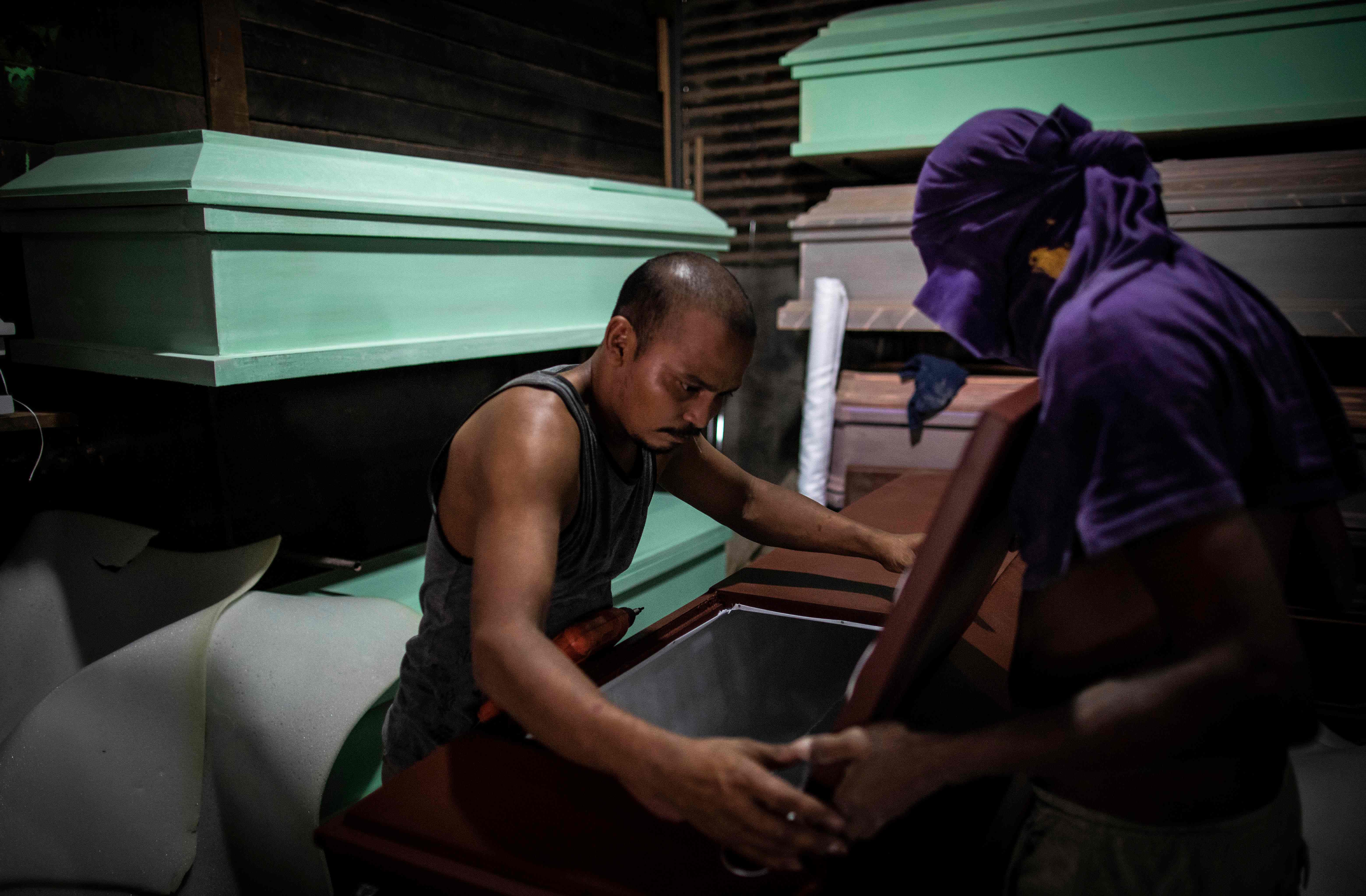 Men work in the making of coffins amid the new coronavirus pandemic at La Amistad Funeral Home in Managua on May 22, 2020. - Carpenters work exhausting shifts to make sealed coffins ahead of the gloomy possible impact of COVID-19 in Nicaragua, where authorities admitted a large number of contagions and deaths in the last week. (Photo by INTI OCON / AFP)