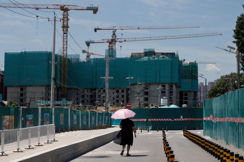 FOTO DE ARCHIVO. Una mujer camina cerca de un sitio de construcción de edifcios de departamentos en Pekín