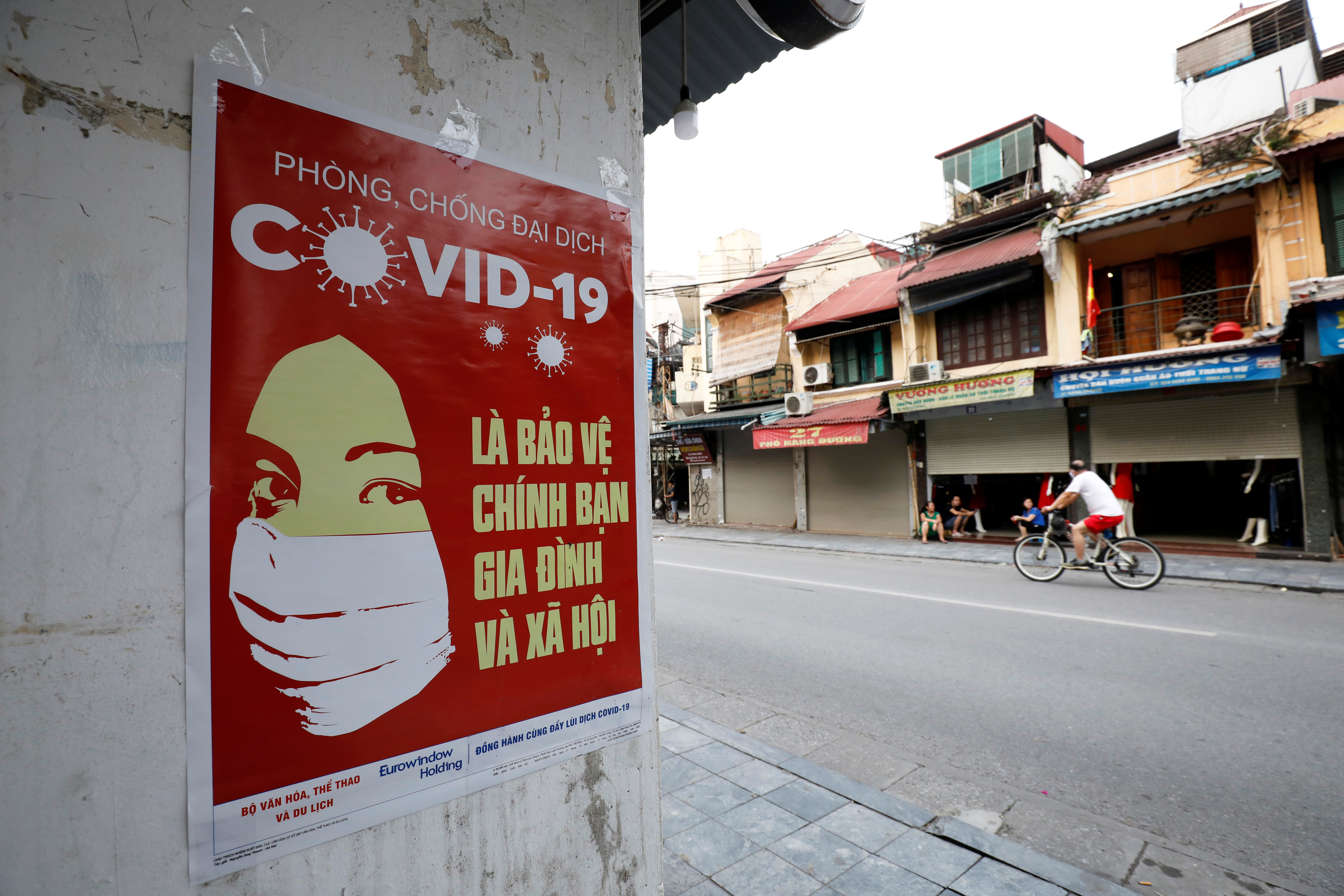 Un póster advierte sobre el COVID-19 en una calle de Hanoi