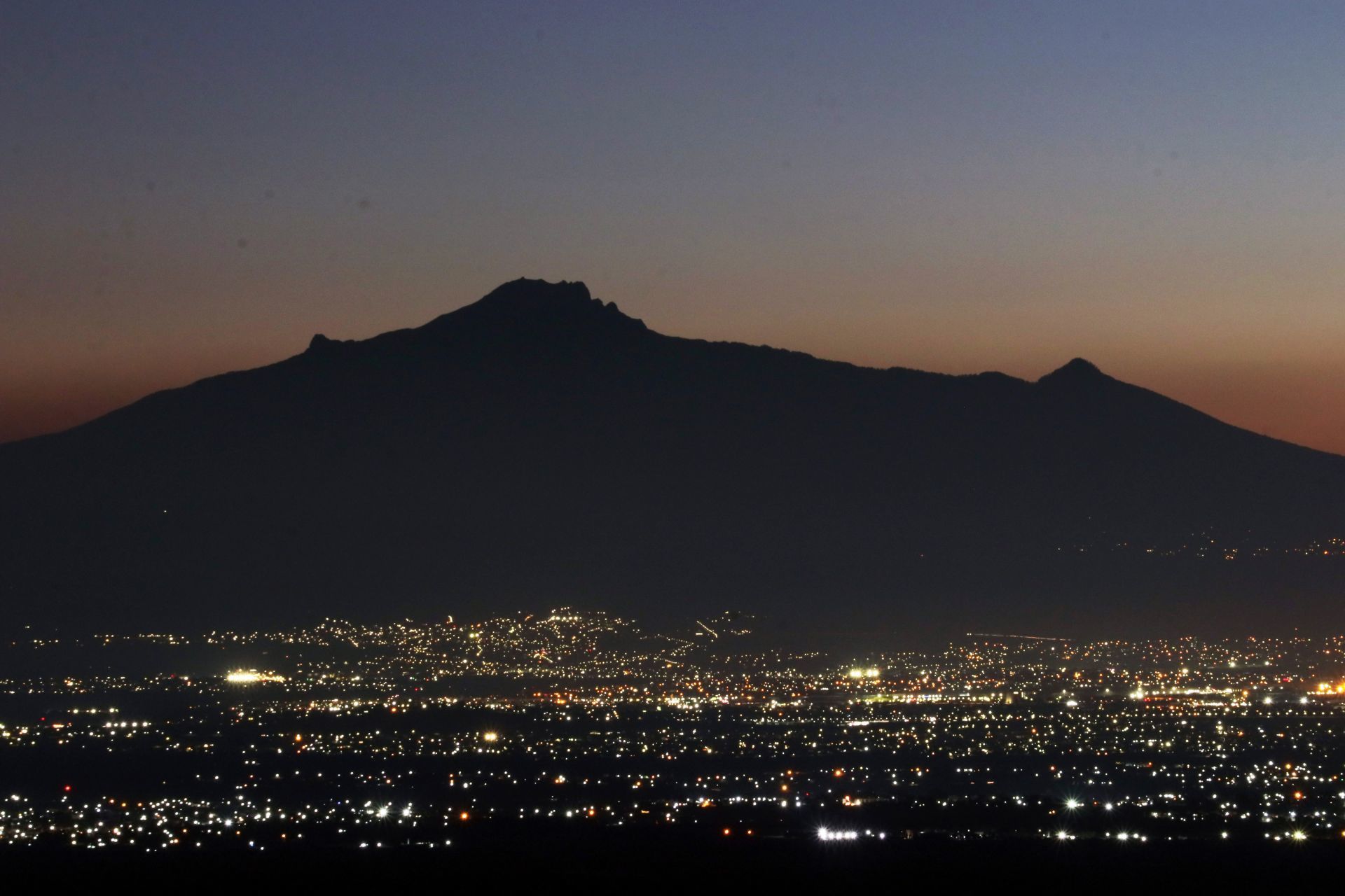 La aurora del amanecer delinea la figura de La Malinche, el Pico de Orizaba e ilumina la ciudad de Puebla. (FOTO: MARGARITO PÉREZ RETANA/CUARTOSCURO.COM)