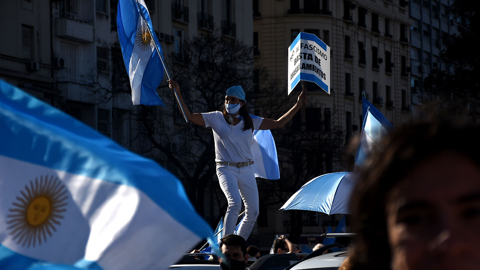 Una mujer protestó con una bandera argentina arriba del techo de un auto