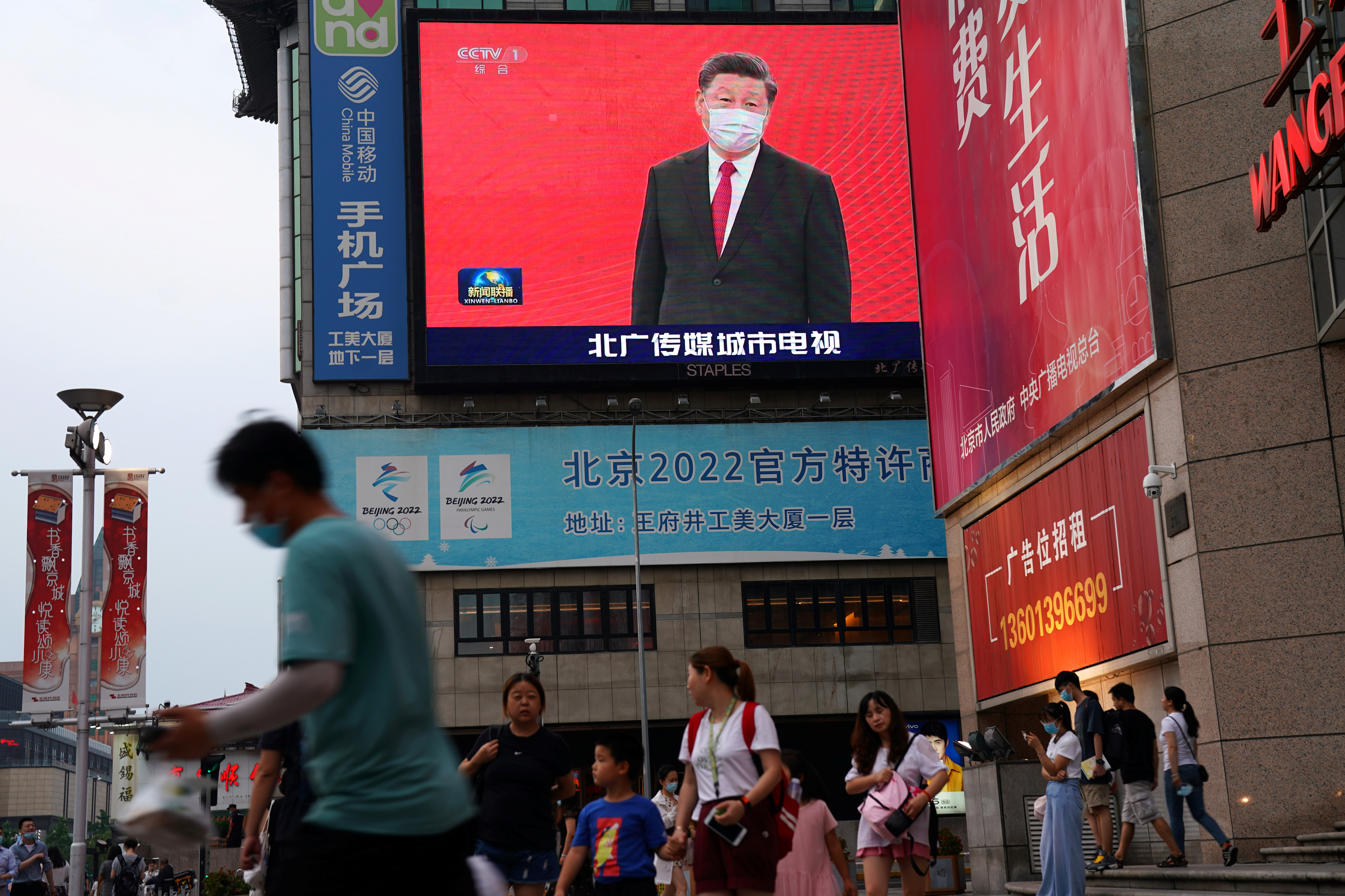 En todas partes. Personas con mascarillas pasan frente a una pantalla gigante que muestra imágenes de noticias del presidente chino Xi Jinping con una mascarilla, en una zona comercial en Beijing (Reuters)