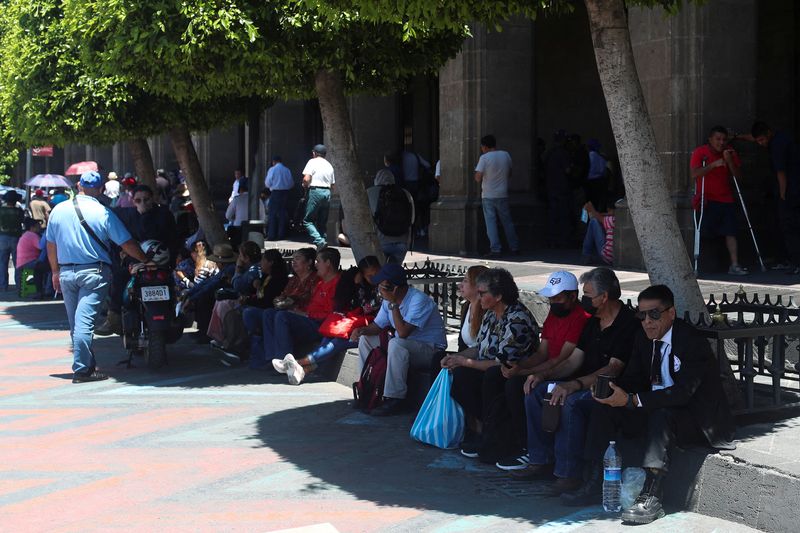 Personas sentadas mientras se cubren del calor durante un periodo de altas temperaturas en Ciudad de México, México 13 de junio de 2023. REUTERS/Henry Romero