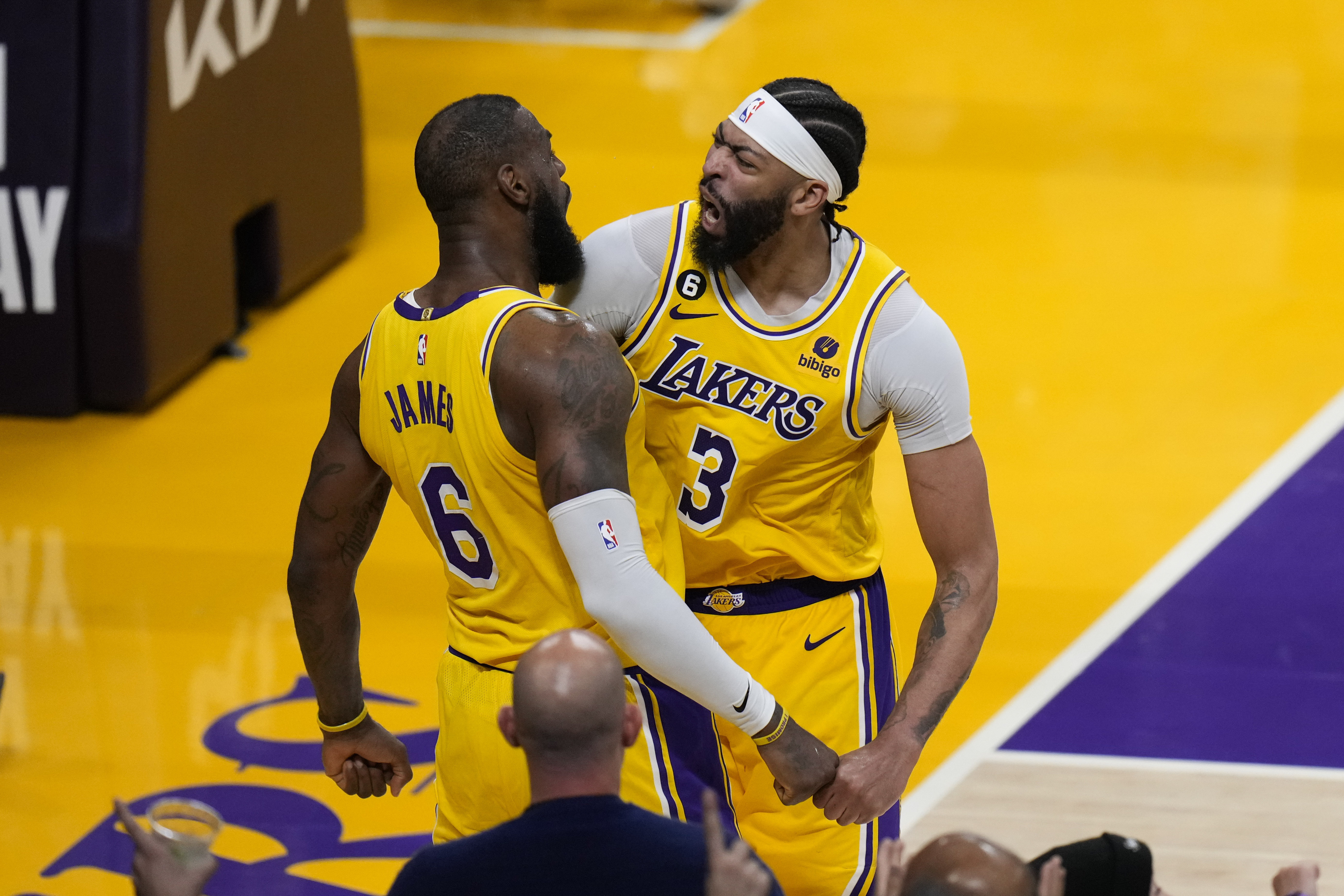 LeBron James (6) y Anthony Davis (3) de los Lakers de Los Ángeles celebran un enceste de James durante el tiempo extra del juego contra los Grizzlies de Memphis en los playoffs de la NBA, el lunes 24 de abril de 2023. (AP Foto/Jae C. Hong)