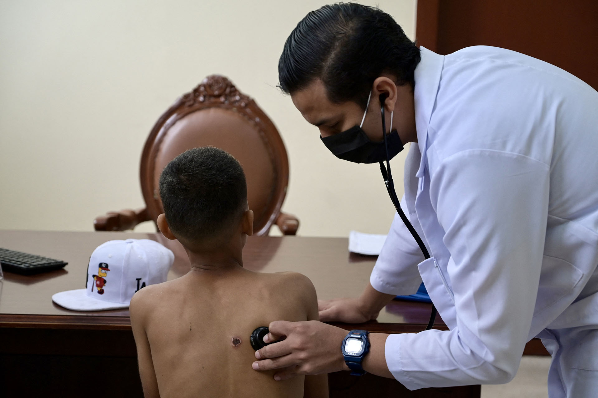 Municipal Program Physician "For a future without drugs", Luis Suárez, cares for a boy with addiction problems after he was shot during a confrontation between gangs.  (Photo by MARCOS PIN / AFP)