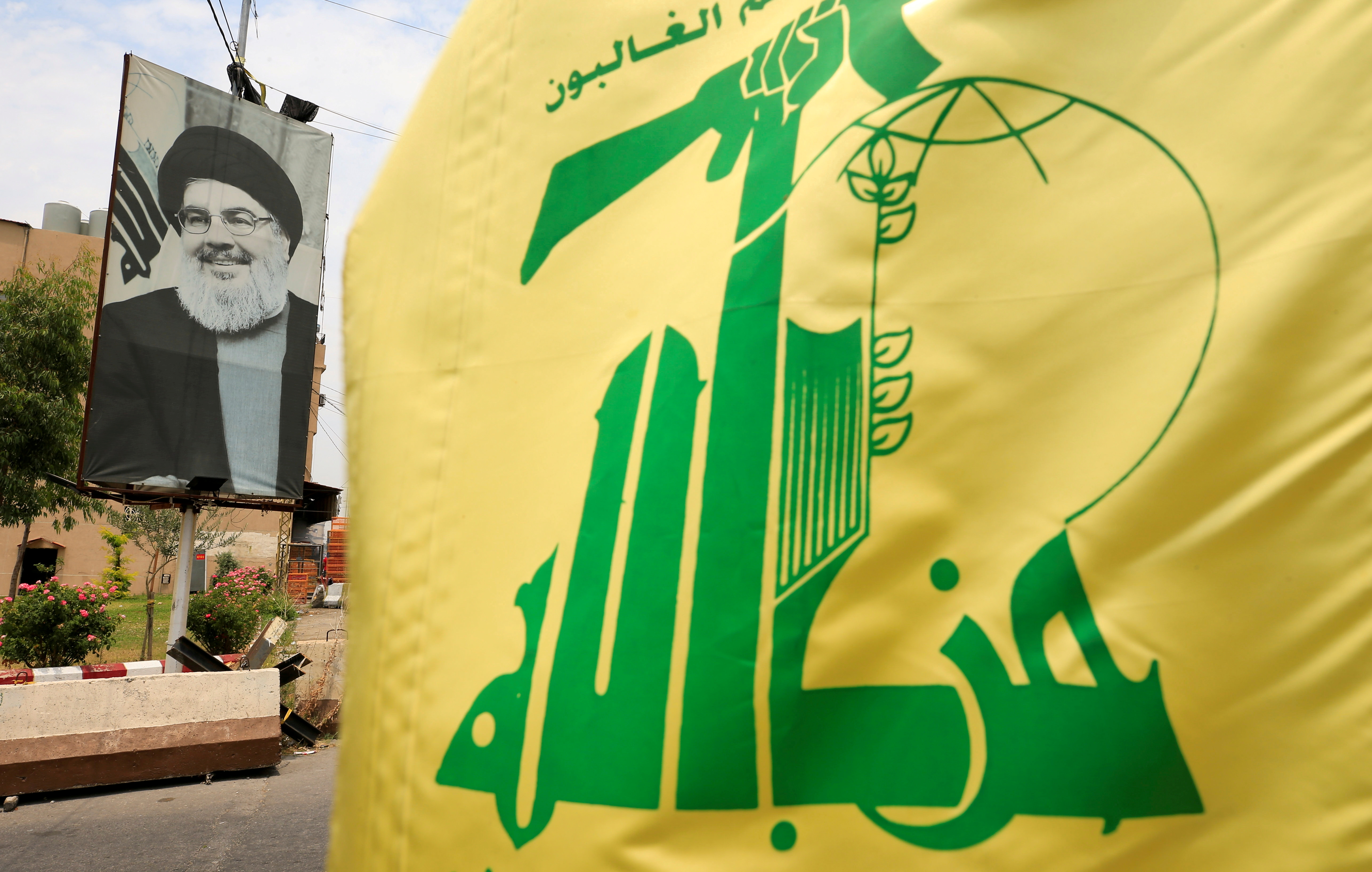 Una bandera de Hezbollah y un cartel que representa al líder libanés de Hezbollah, Sayyed Hassan Nasrallah, en Líbano (Reuters)