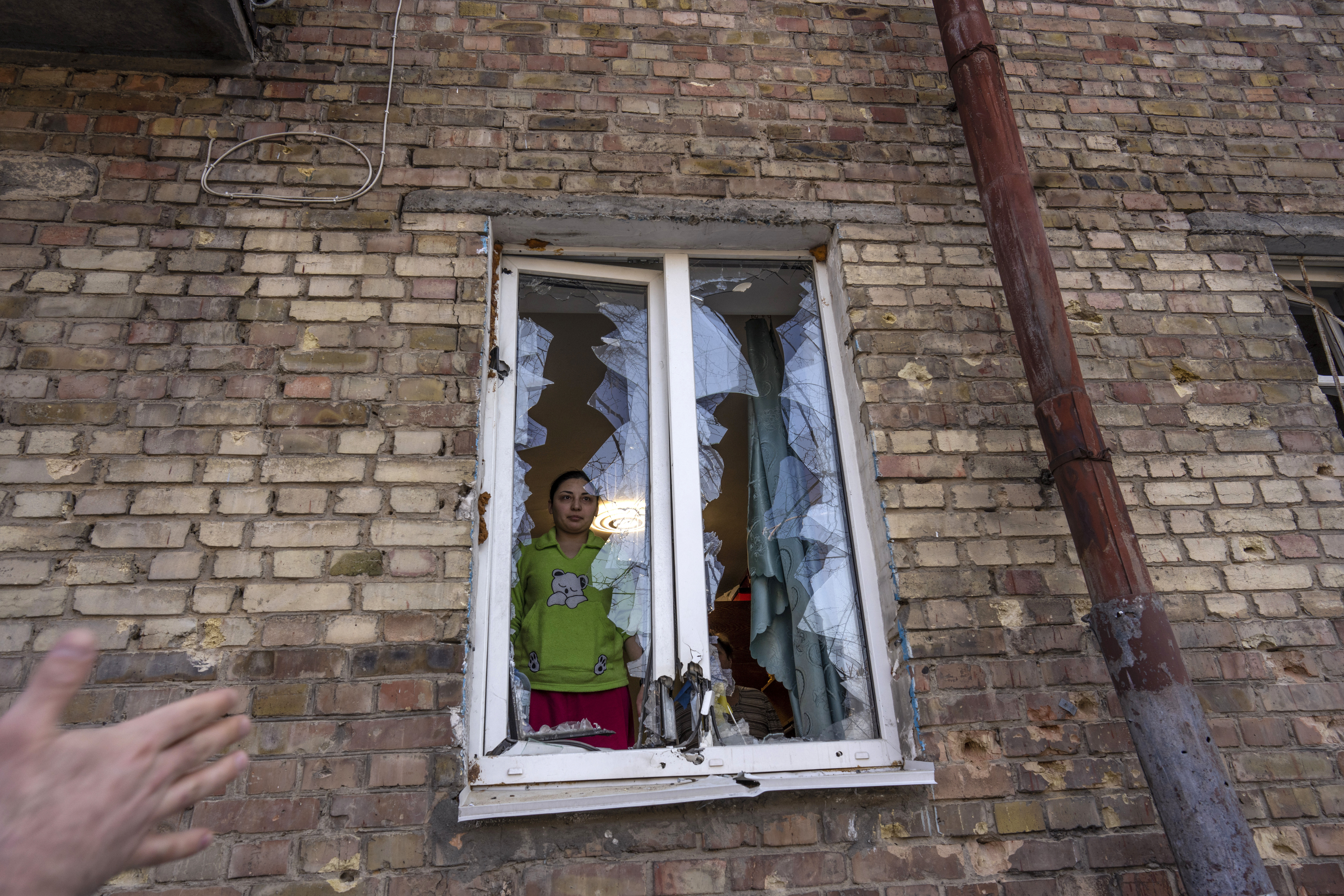 La joven Anna mira a la calle a través de una ventana destruida dentro de su apartamento, dañado por los bombardeos, en Kiev, Ucrania, el miércoles 23 de marzo de 2022 (AP Photo/Rodrigo Abd)