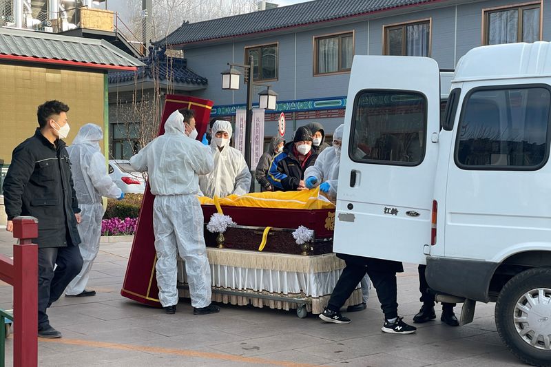 Trabajadores con trajes protectores trasladan un cuerpo en un ataúd en una funeraria en Beijing (Reuters)