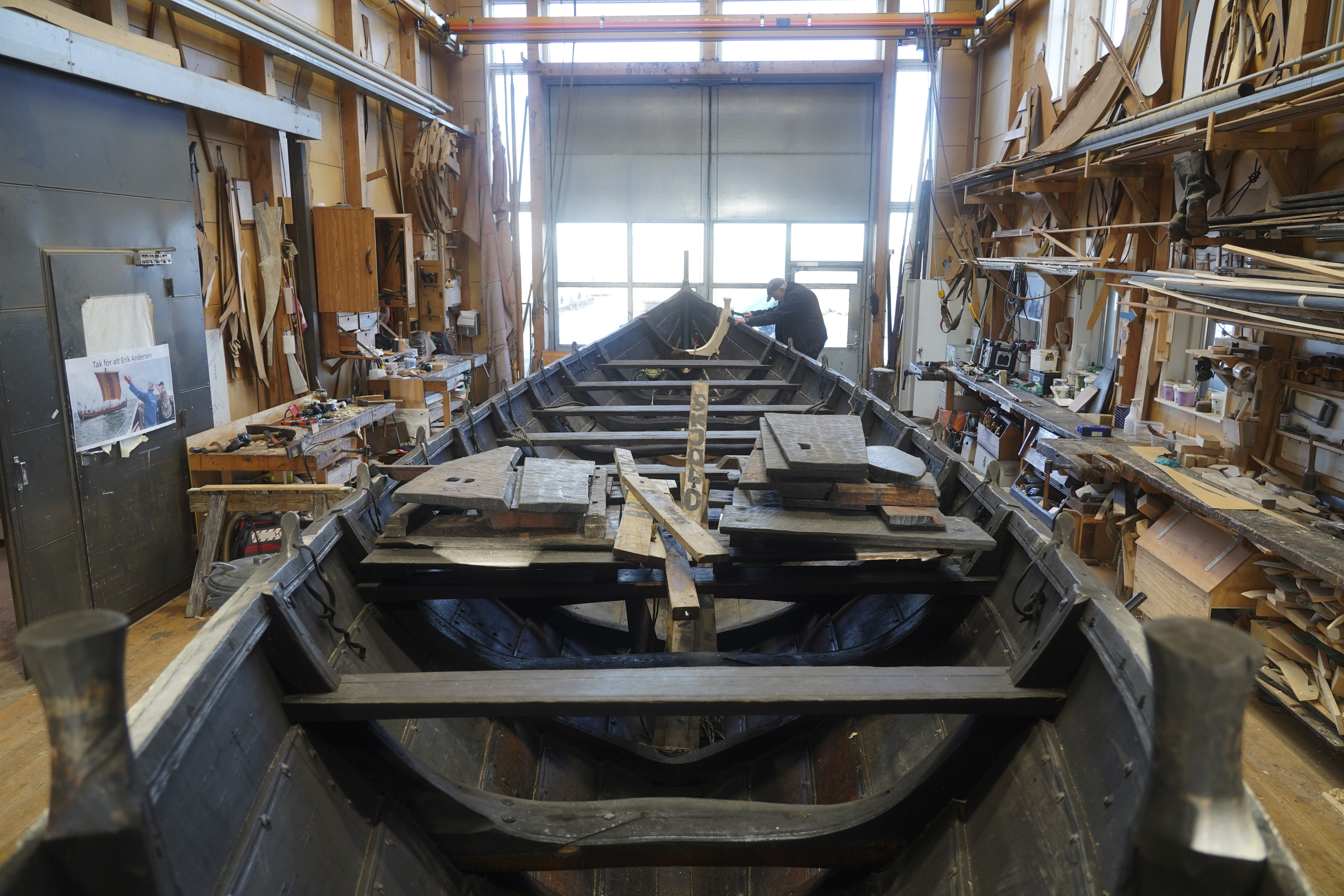 Un hombre repara un bote de remos de madera de 10 metros, construido según la tradición nórdica de los botes de escoria, en el astillero del Museo de Barcos Vikingos. Roskilde, Dinamarca, lunes 17 de enero de 2022.  (Foto AP/James Brooks)

