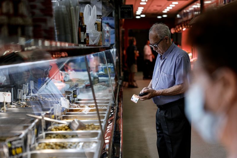 Un cliente se prepara para pagar en la tienda de comestibles Hermanos Cadenas en un mercado de Madrid, España, 12 de agosto de 2022. REUTERS/Susana Vera