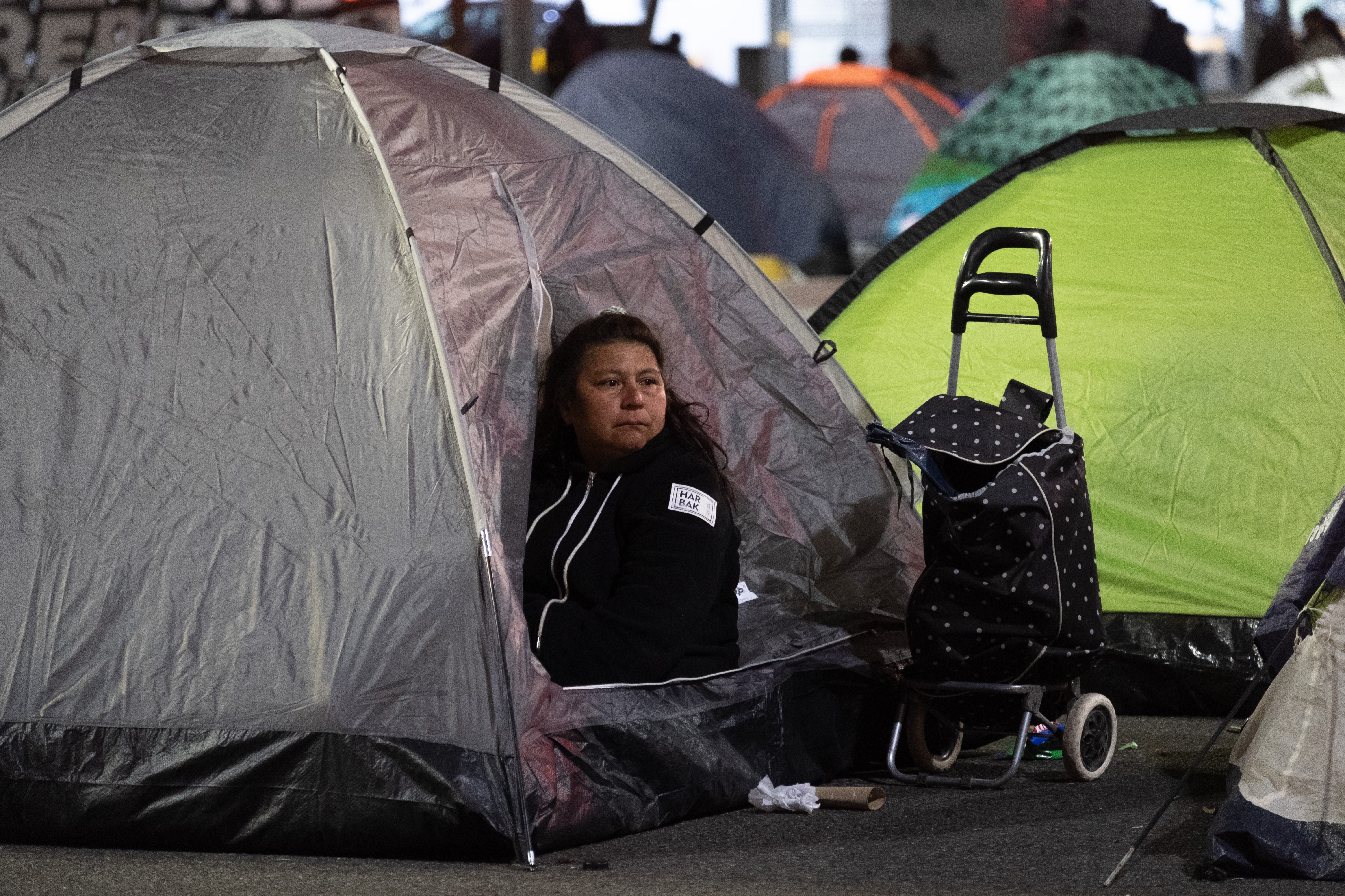 Un carrito de compras negro con lunares blancos acompaña a una de las manifestantes que se asoma desde el interior de una de las carpas montada en el 9 de Julio 