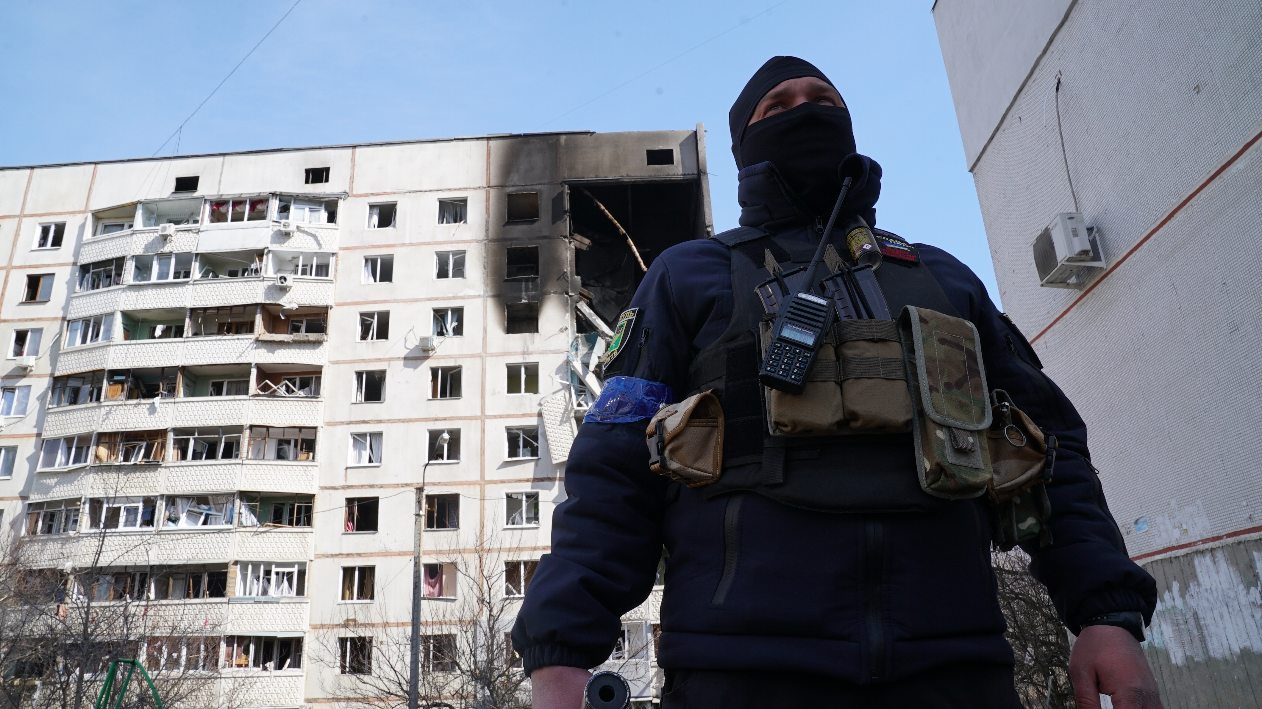 Un policía ucraniano y atrás un edificio destruido por los bombardeos rusos (Joaquín Sánchez Mariño)
