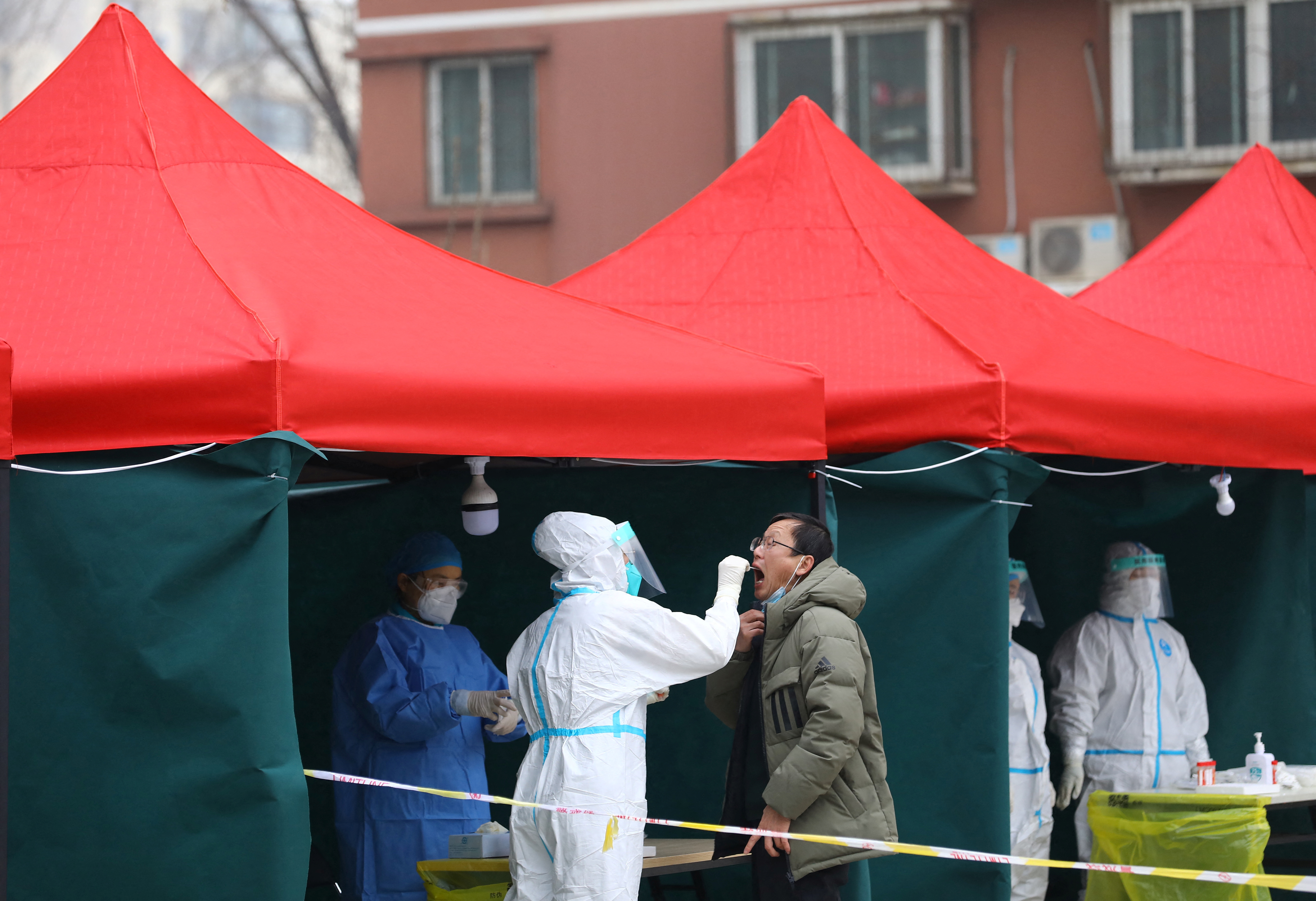 Un trabajador médico recolecta una muestra de hisopo de un residente en un sitio de prueba de ácido nucleico improvisado en un complejo residencial, luego de nuevos casos confirmados de la enfermedad por coronavirus (COVID-19), en Beijing, China, el 24 de enero de 2022. REUTERS/Tingshu Wang