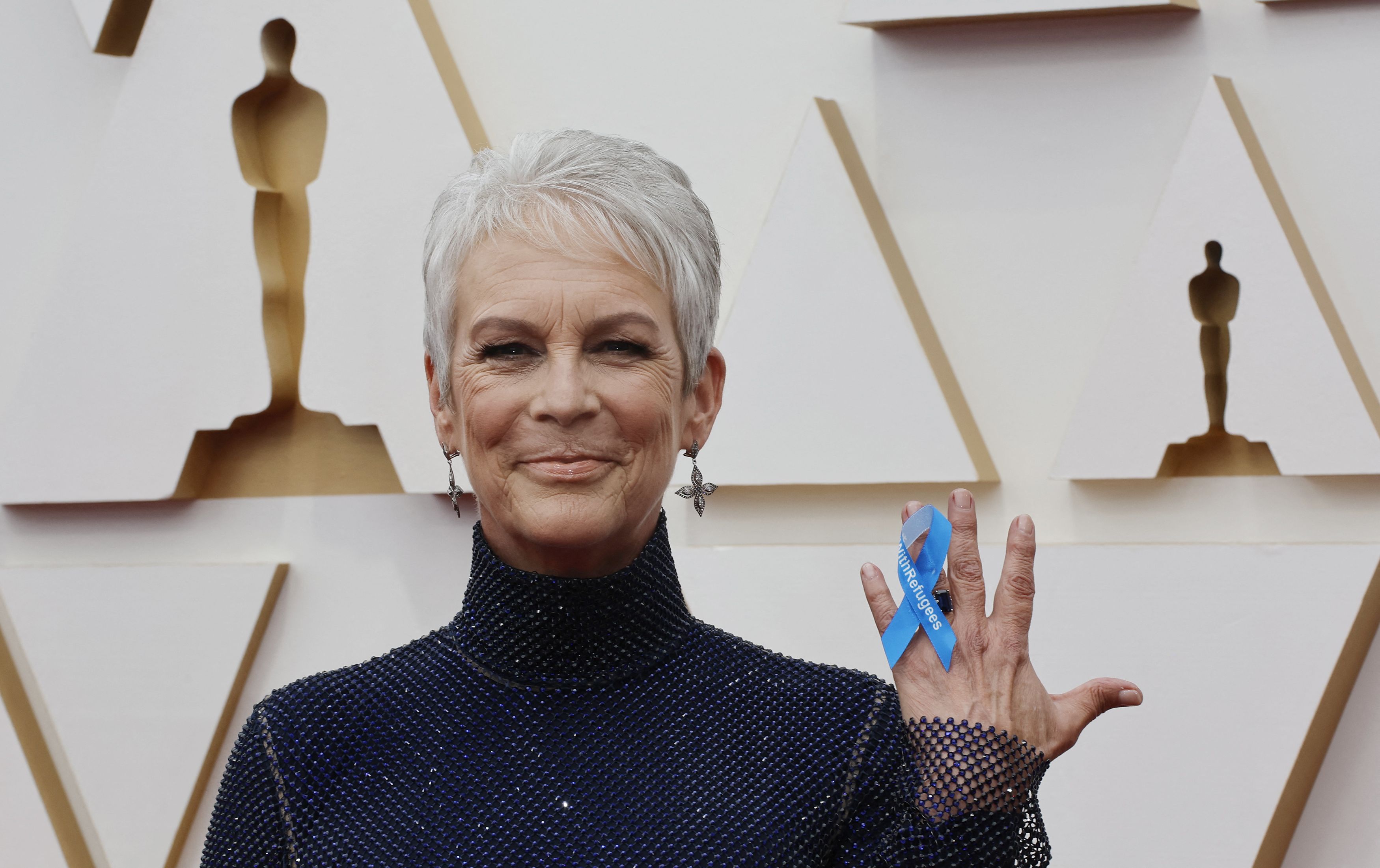 Jamie Lee Curtis holds a ribbon reading "With Refugees" supporting global refugees as she poses on the red carpet during the Oscars arrivals at the 94th Academy Awards in Hollywood, Los Angeles, California, U.S., March 27, 2022. REUTERS/Eric Gaillard