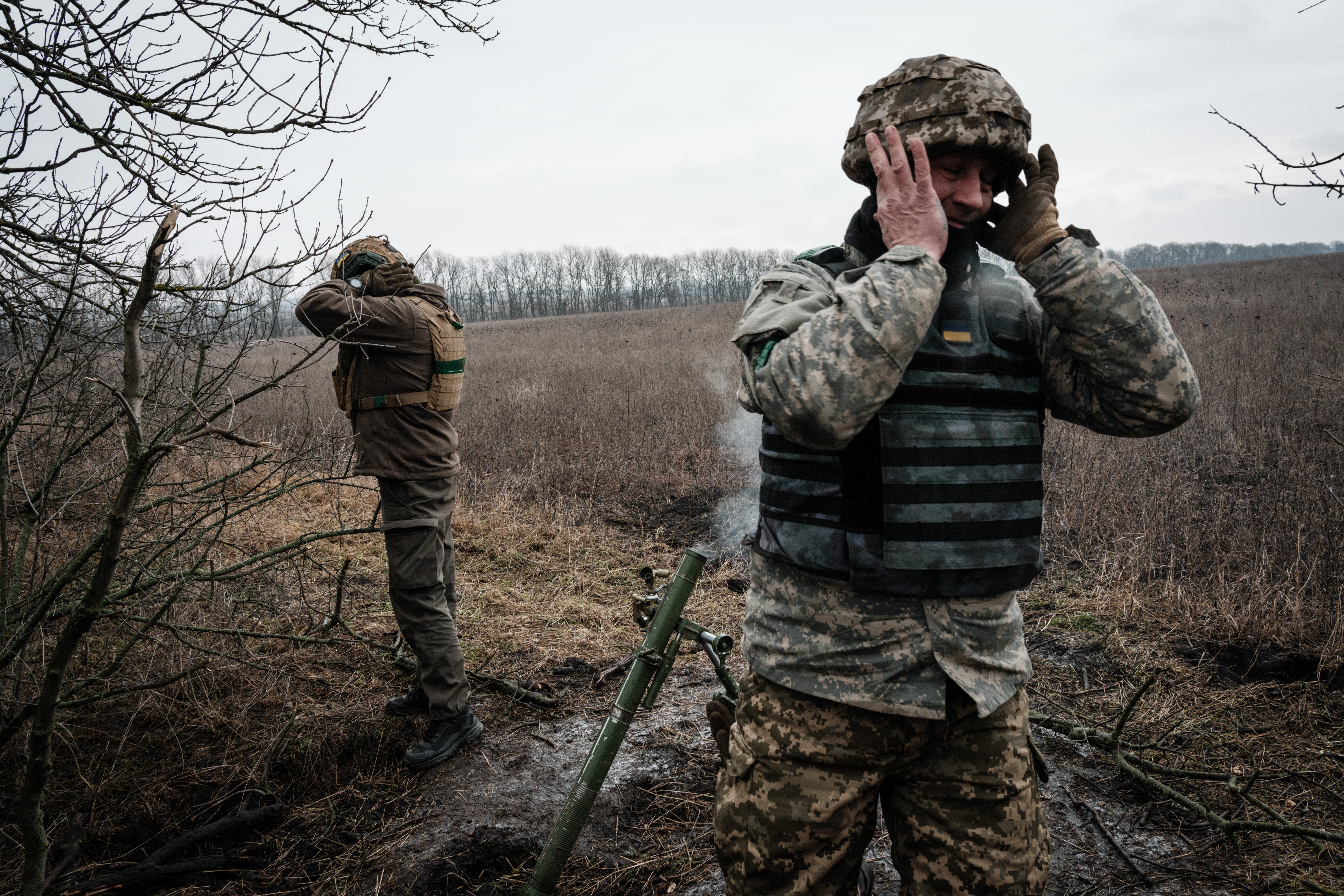 Los militares ucranianos se tapan los oídos mientras disparan un mortero de 60 mm hacia las posiciones rusas cerca de la línea del frente en la región de Donetsk, el 31 de enero de 2023 (Foto de YASUYOSHI CHIBA / AFP)