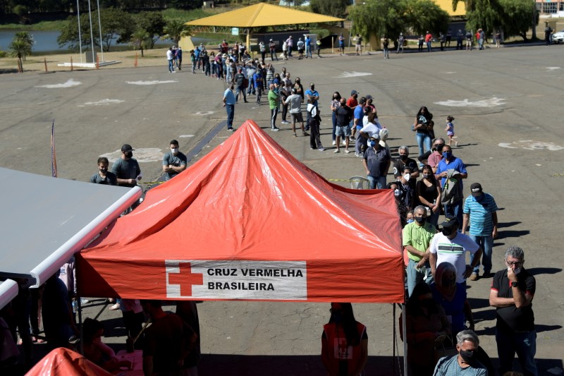 Residentes hacen fila frente al "Busao da Vacina" o Gran autobús de la vacuna, un proyecto de la Cruz Roja Brasileña, en asociación con el gobierno del estado de Minas Gerais para vacunar a la gente contra la enfermedad del coronavirus (COVID-19) en Ouro Branco, Brasil (REUTERS/Washington Alves/Archivo)