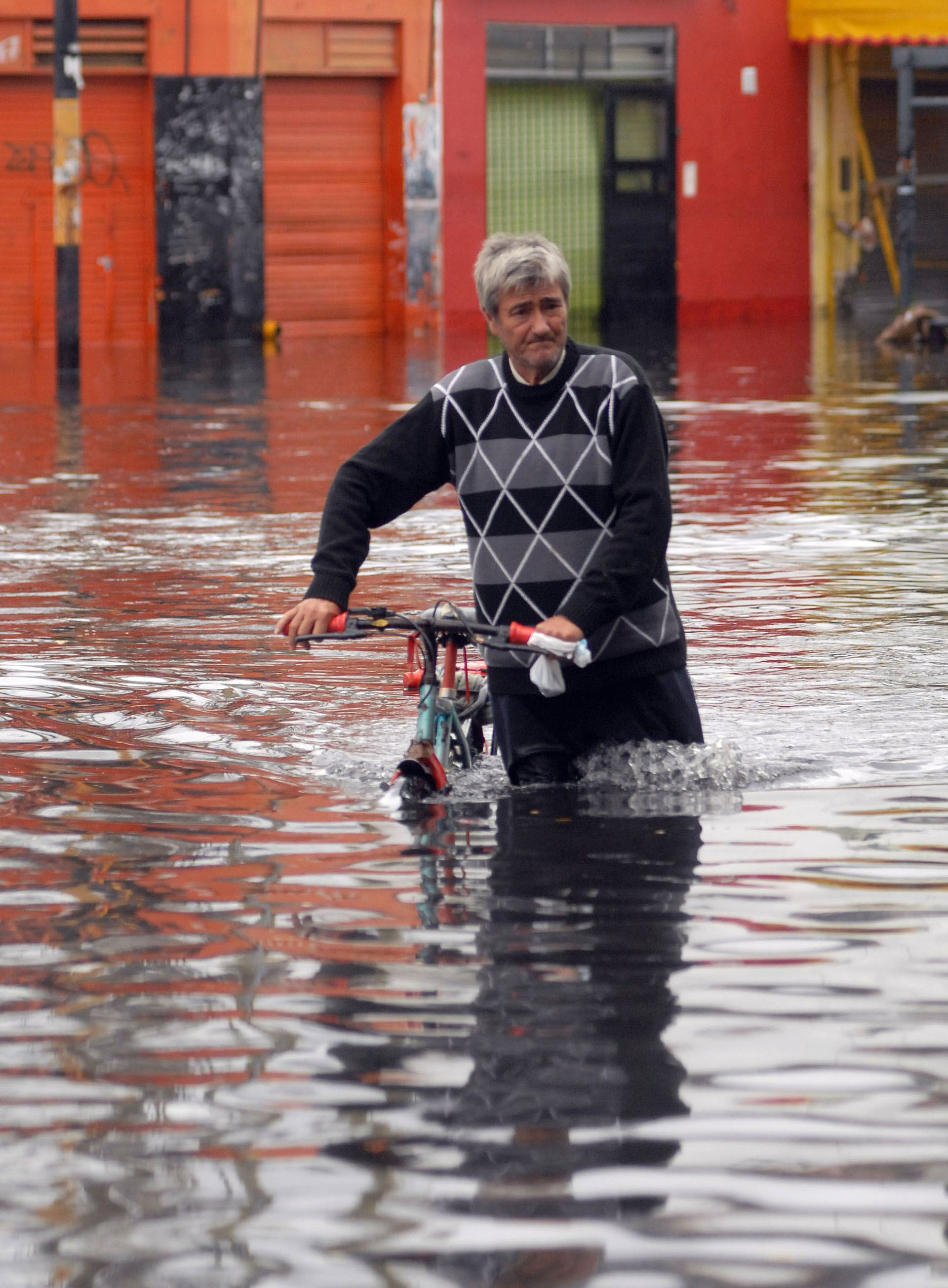 Un hombre lleva como puede su bicicleta. El agua alcanzó en algunas zonas 1.80 metro (NA)