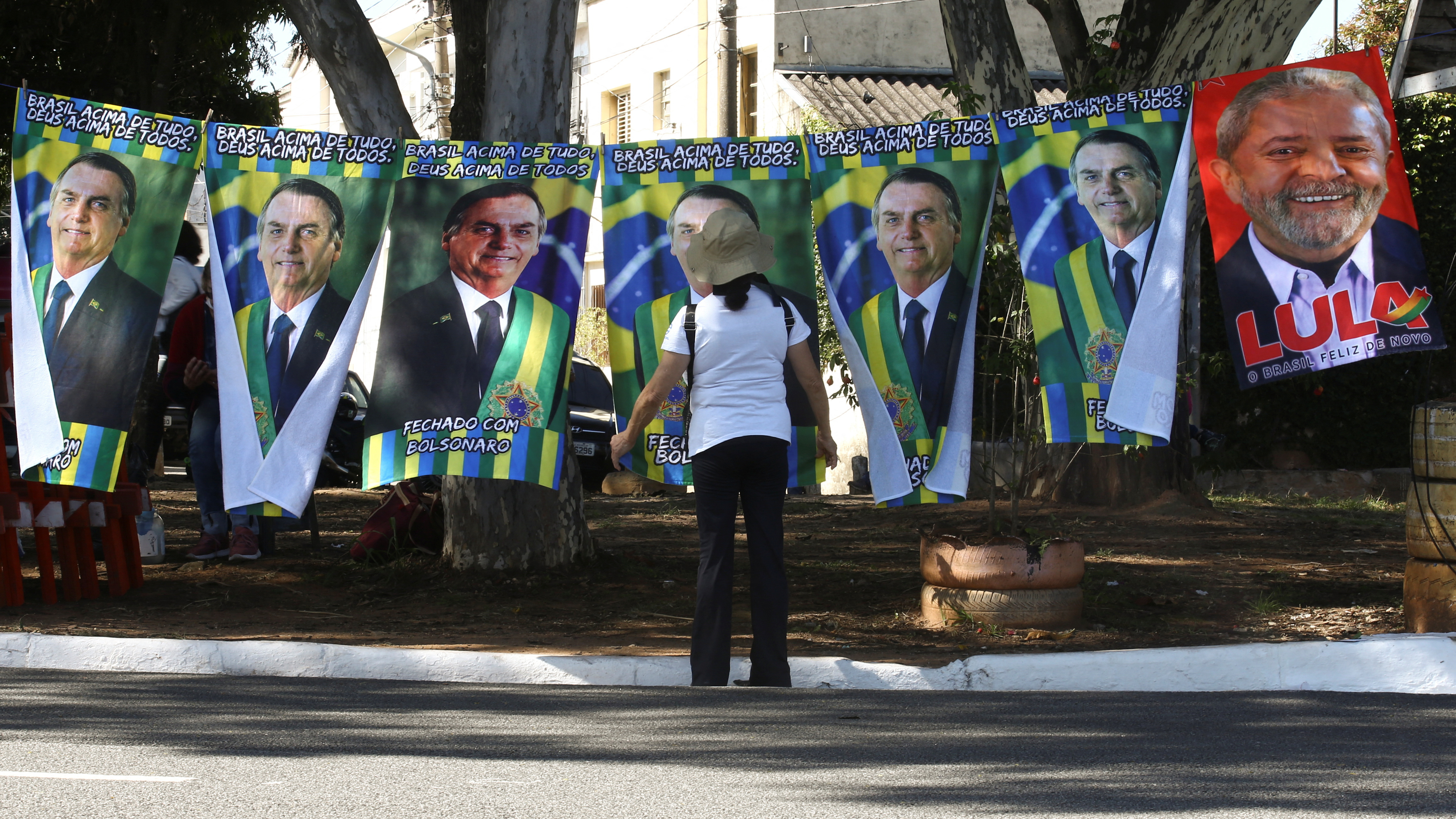 Una persona junto a carteles de los candidatos presidenciales Jair Bolsonaro y Luiz Inacio Lula da Silva  (REUTERS/Carla Carniel)