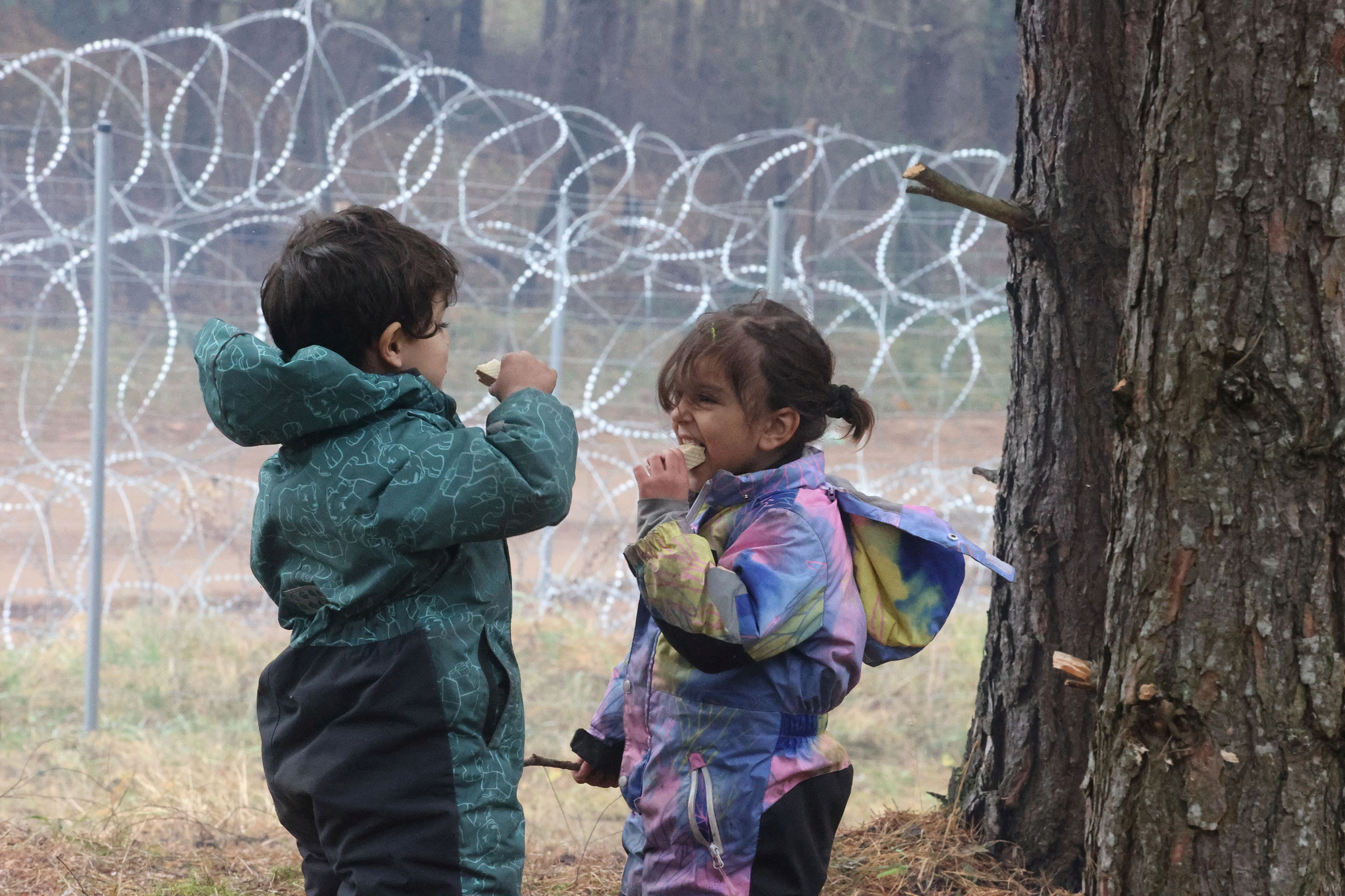 Los niños comen en un campamento improvisado para migrantes en la frontera bielorrusa-polaca en la región de Grodno, Bielorrusia 13 de noviembre de 2021. Leonid Scheglov / BelTA / Handout via REUTERS