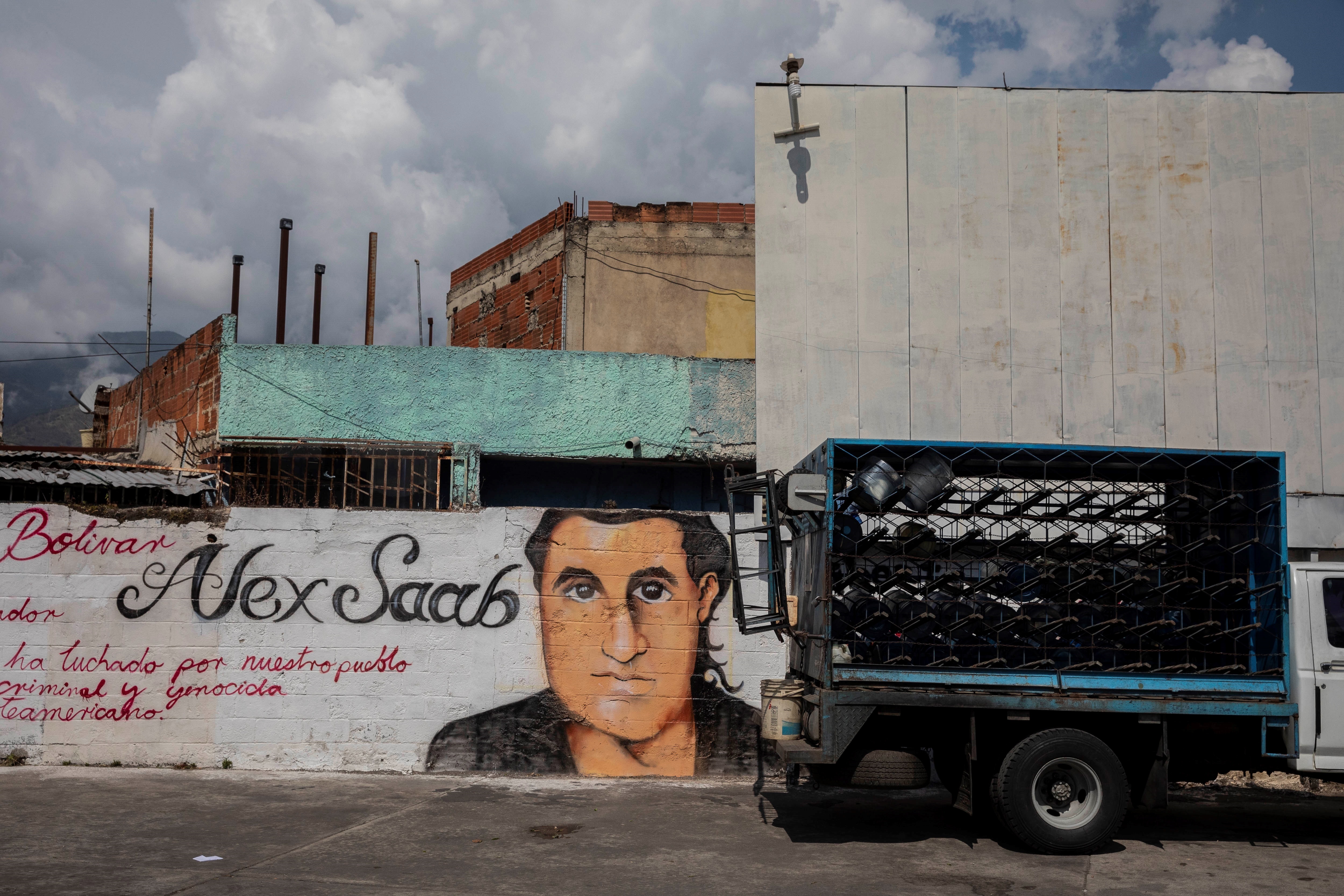 Un pequeño camión pasa junto a un grafiti con la imagen del rostro de Alex Saab en Caracas (EFE)
