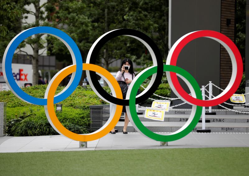 Una mujer utilizando mascarilla toma una fotografía a os anillos olímpicos frente al Estadio Nacional de Tokio, Japón October 14, 2020. REUTERS/Kim Kyung-Hoon