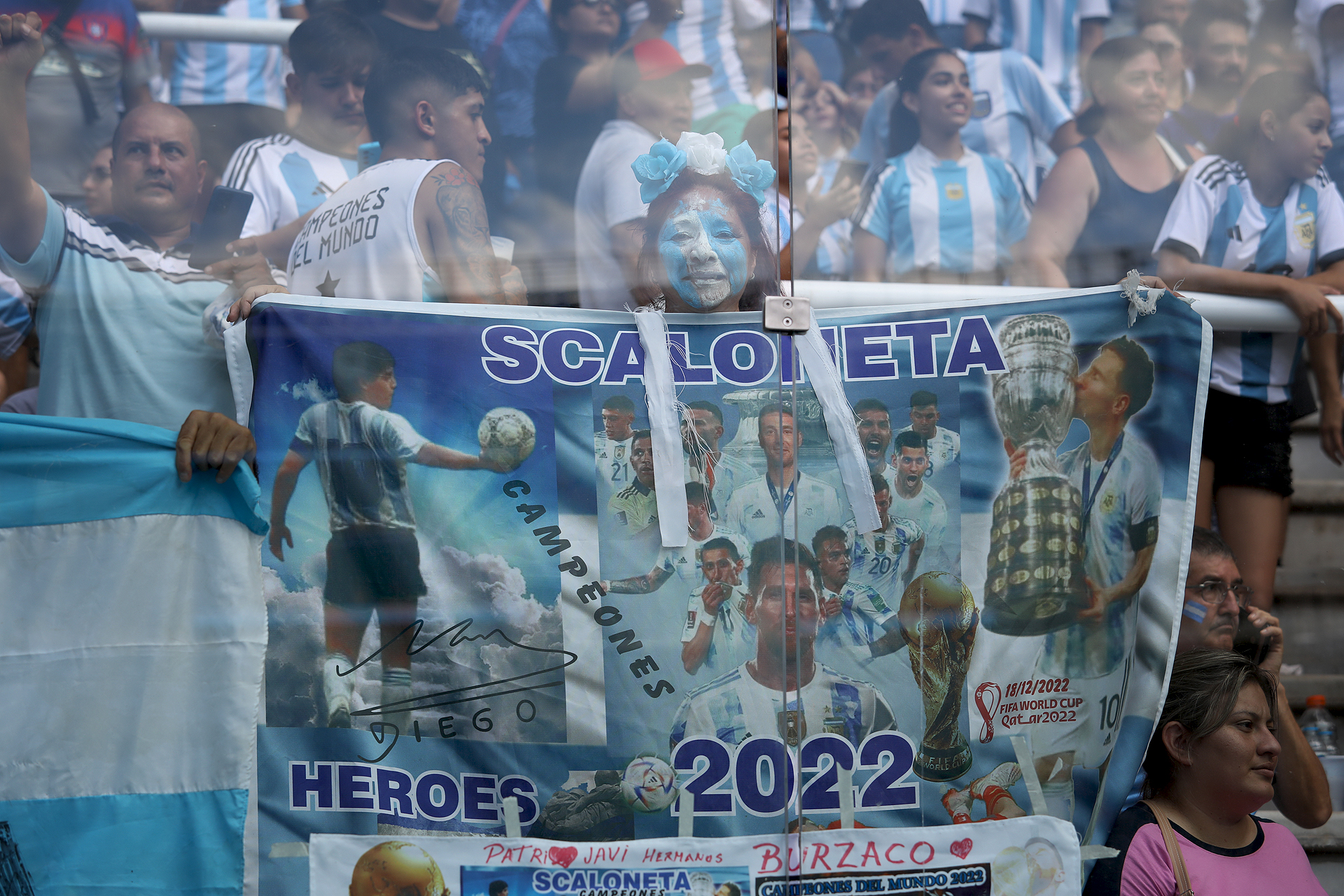 Íconos albicelestes: una bandera de la Scaloneta con imágenes de Lionel Messi, sus compañeros, el entrenador y Diego Maradona