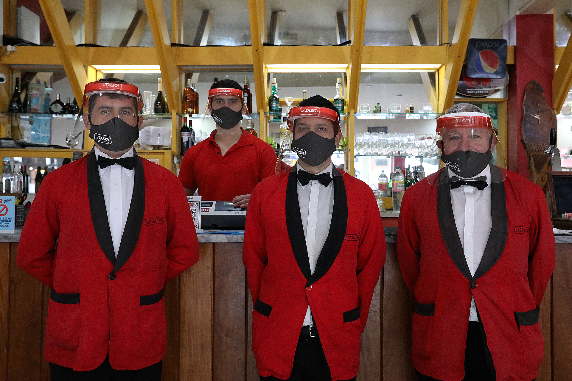 A su tradicional uniforme de saco rojo y moño negro, los camareros de