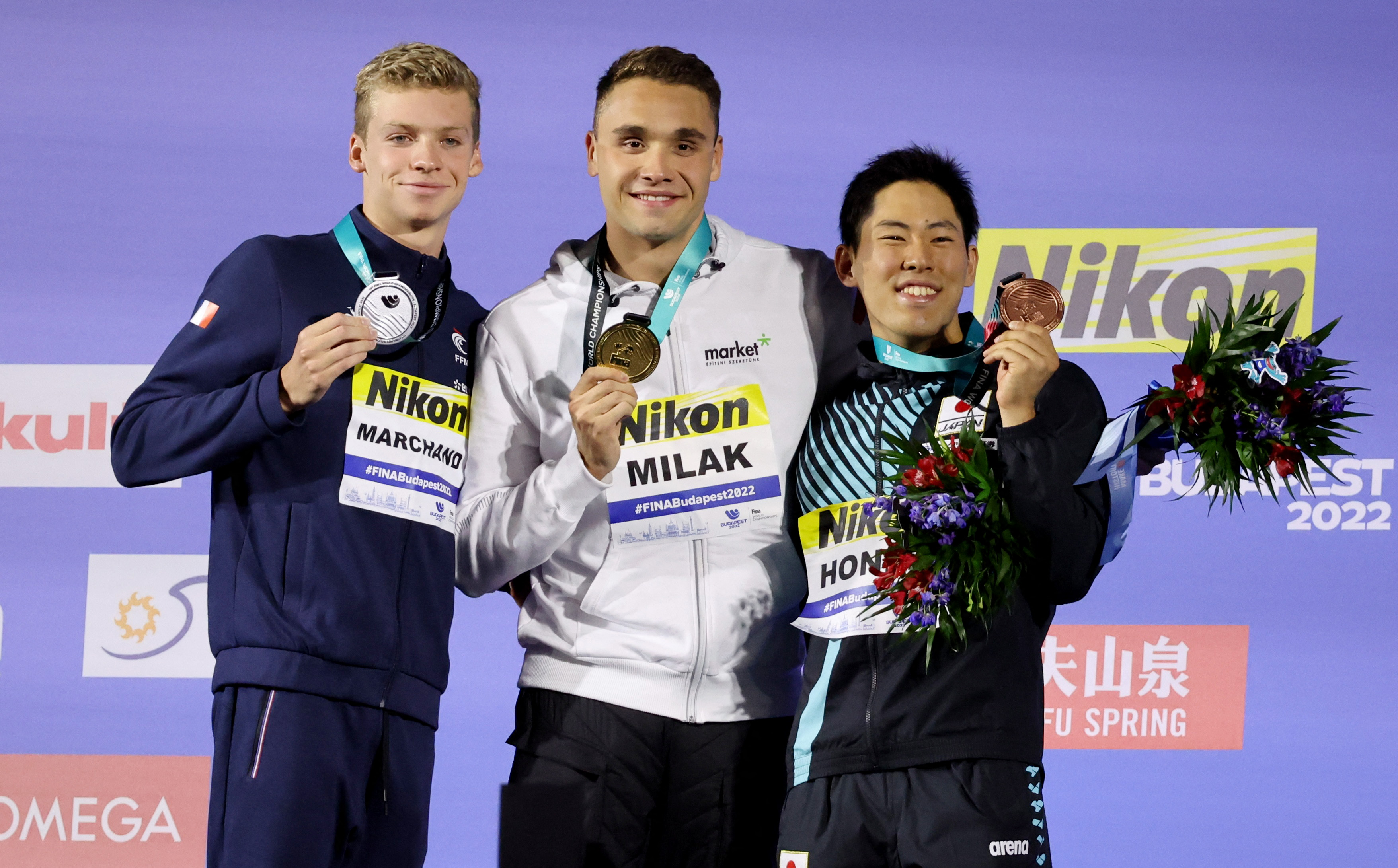 Swimming - FINA World Championships - Budapest, Hungary - June 21, 2022 Men's 200m butterfly gold medallist, Hungary's Kristof Milak celebrates on the podium with silver medallist, France's Leon Marchand and bronze medallist, Japan's Tomoru Honda REUTERS/Antonio Bronic