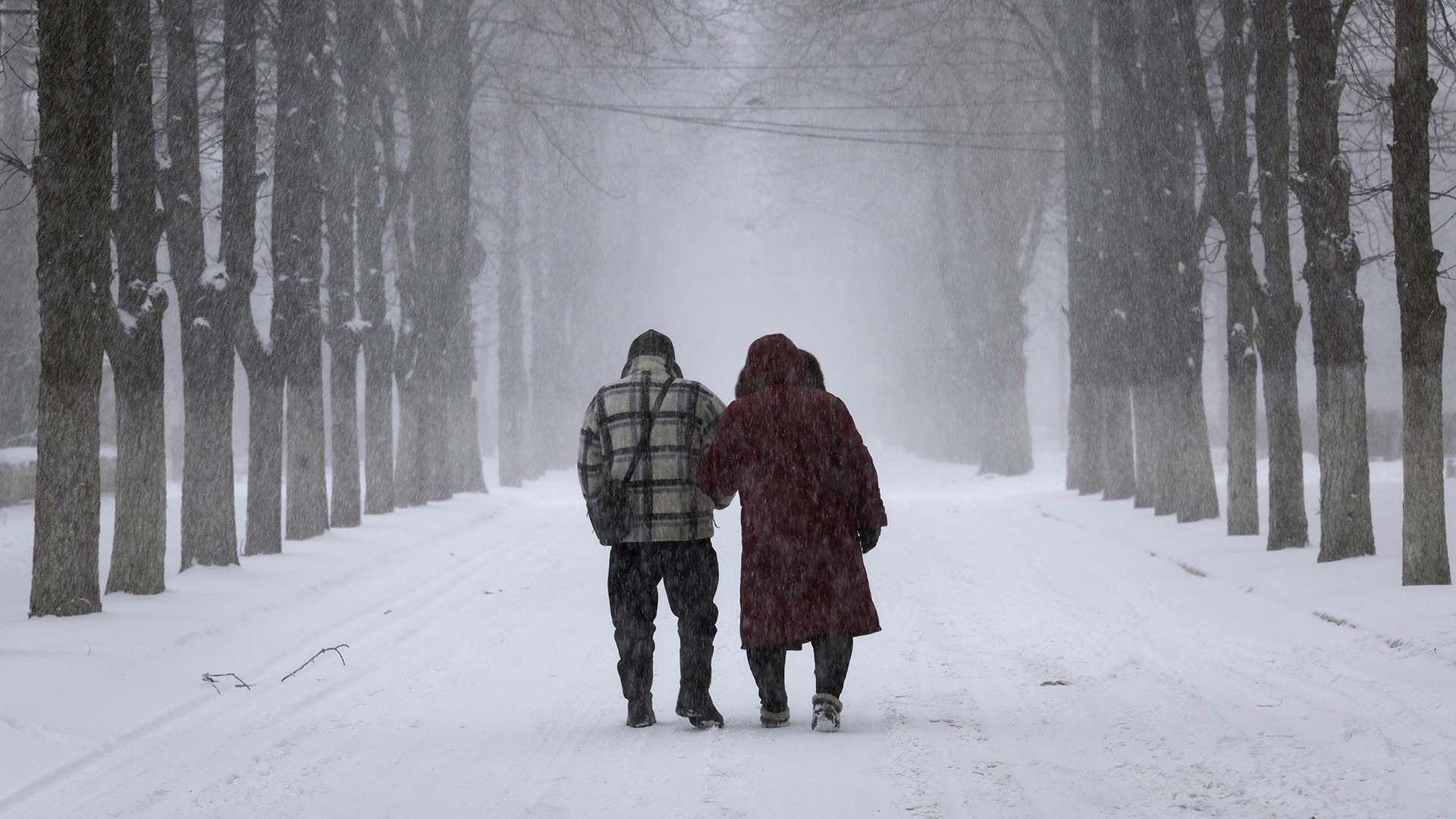 El matrimonio de Kolya y Olya, de 57 años, camina bajo una tormenta de nieve mientras el sonido de la artillería retumba a su alrededor el 12 de febrero de 2023 en Chasiv Yar, Ucrania, en la región oriental del Donbás.