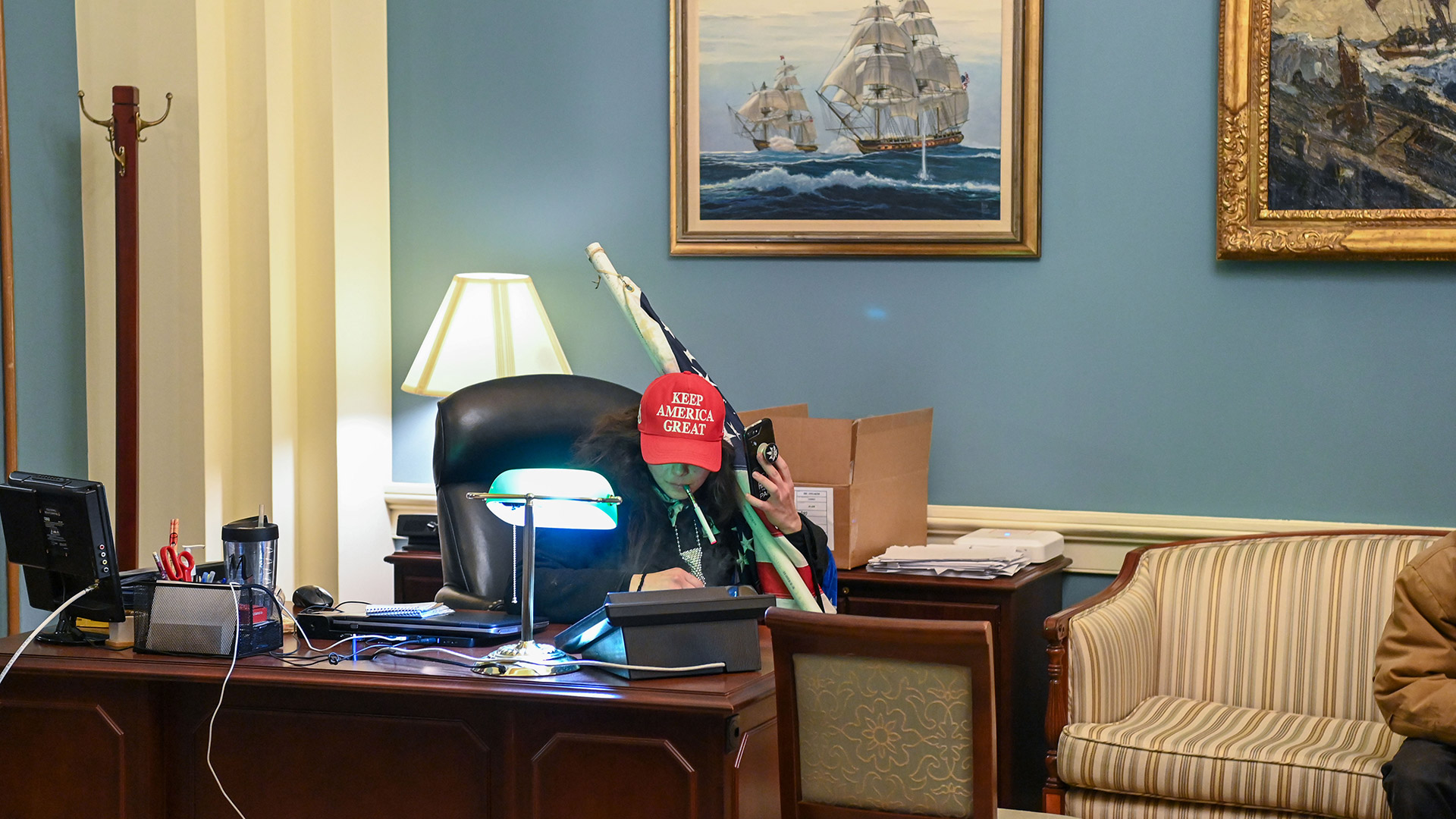 Un partidario de Trump se sienta en un escritorio después de invadir el edificio del Capitolio  (Foto de Saul LOEB / AFP)