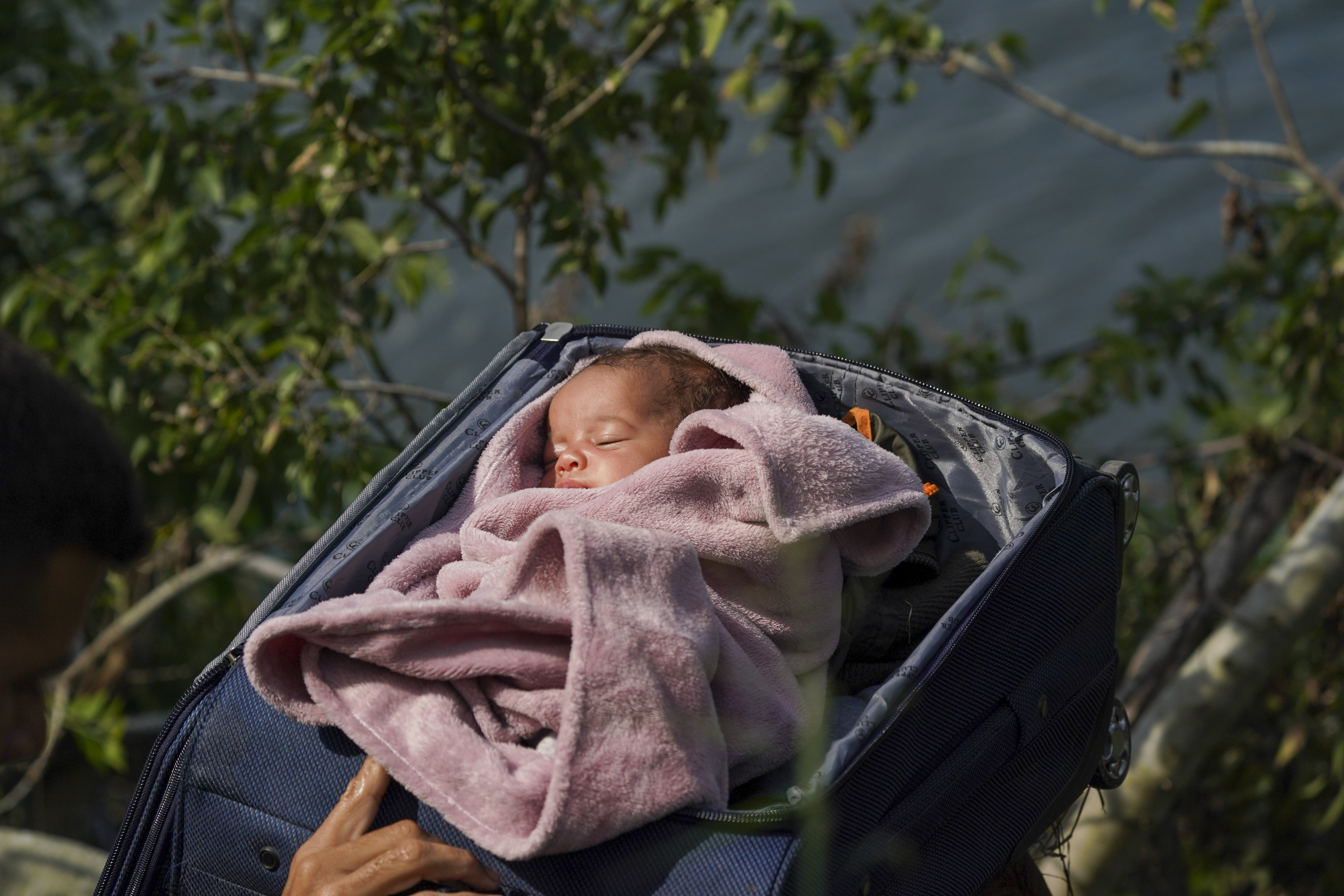 A migrant baby is carried in a suitcase across the Rio Grande, from Matamoros, Mexico, to the United States, on May 10, 2023. Migrants were rushing across the border before U.S.-imposed asylum restrictions expired. United on the pandemic, a shift that threatens to place a historic burden on the country's battered immigration system.  (AP Photo/Fernando Llano)