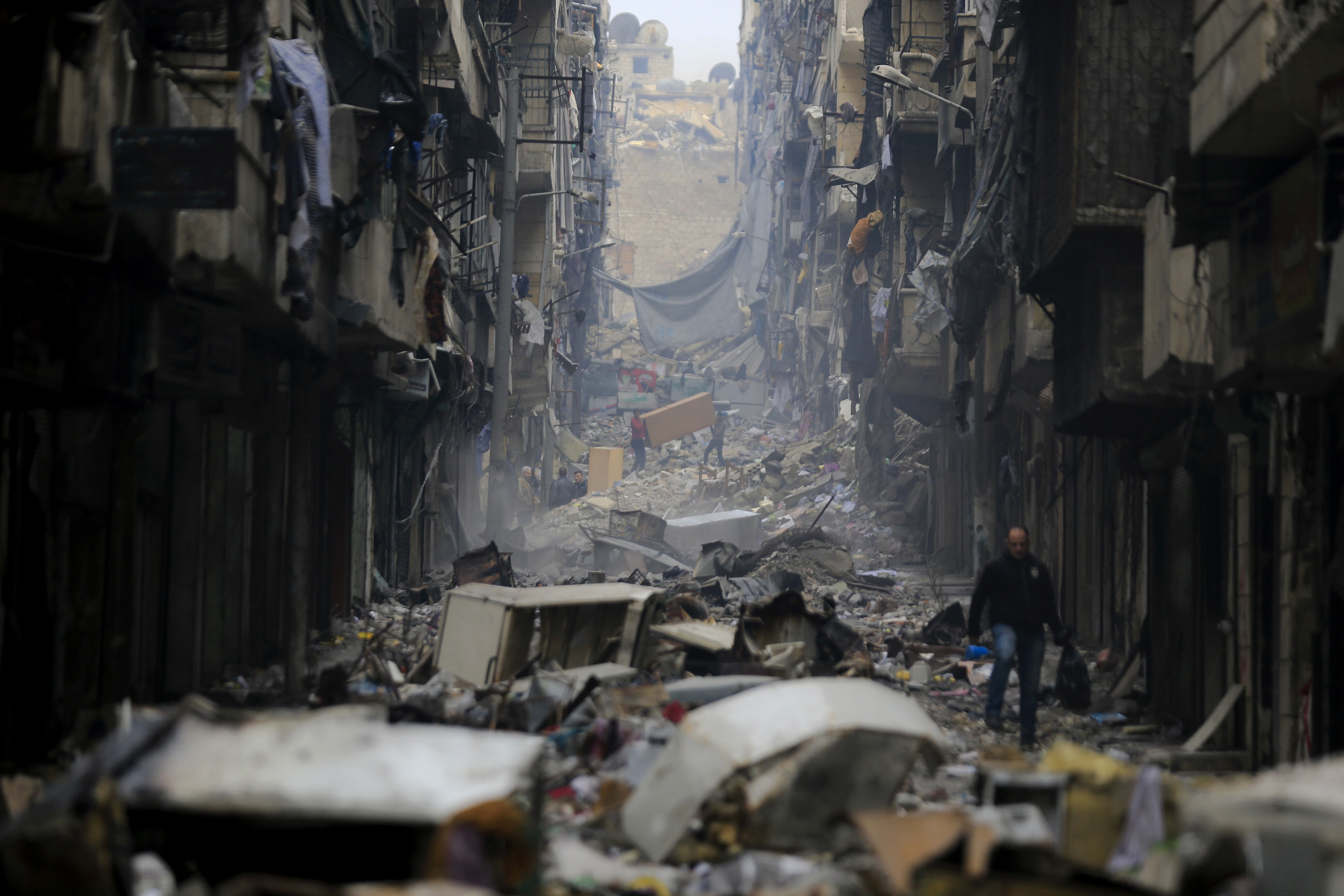 Varios residentes caminan a través de la destrucción causada por la guerra en el barrio Salaheddine de Alepo, Siria (AP Foto/Hassan Ammar, Archivo)