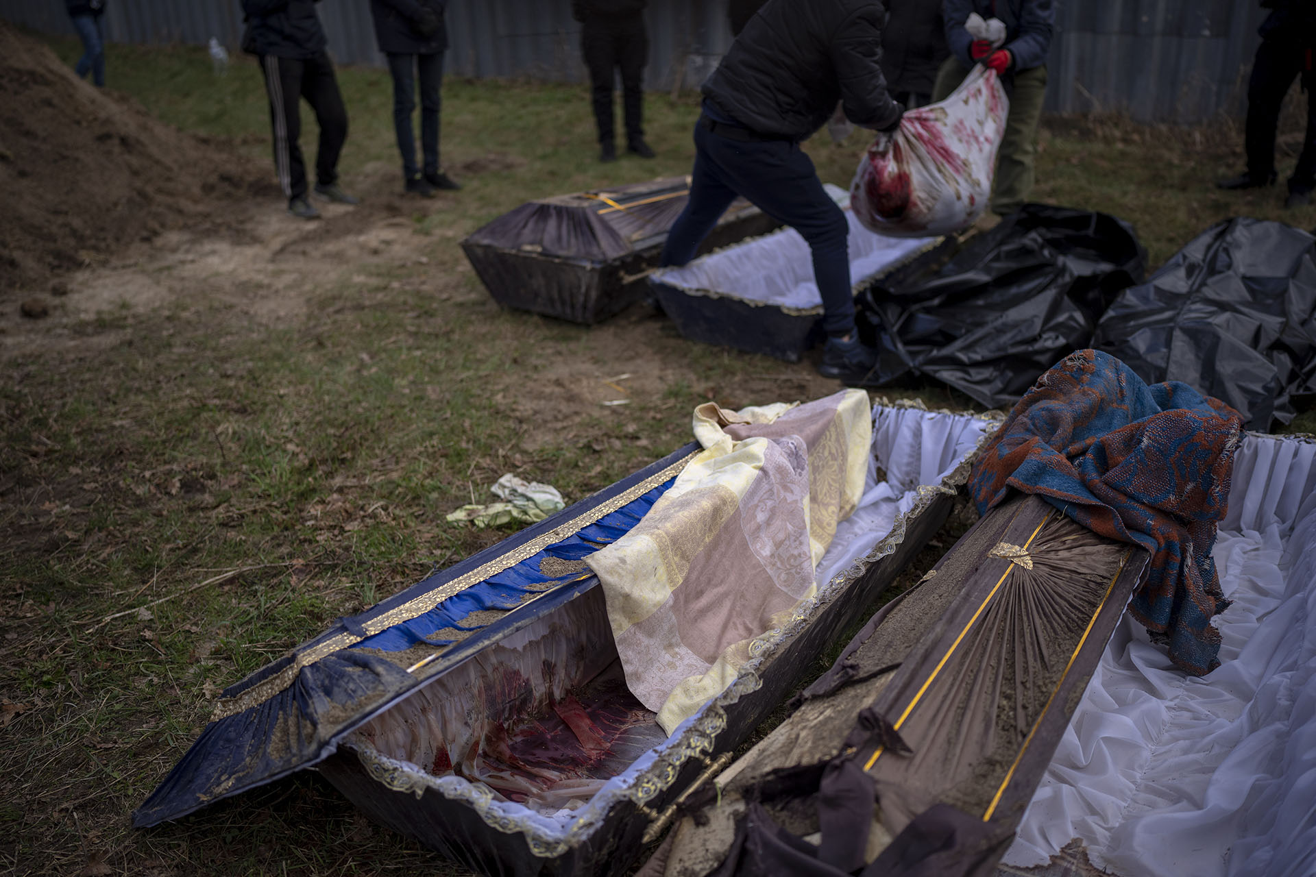 Voluntarios pusieron en una bolsa el cuerpo de un civil asesinado por el ejército ruso, después de haber sido sacado de una fosa común, durante una exhumación en Mykulychi, Ucrania. (AP Foto/Emilio Morenatti) 