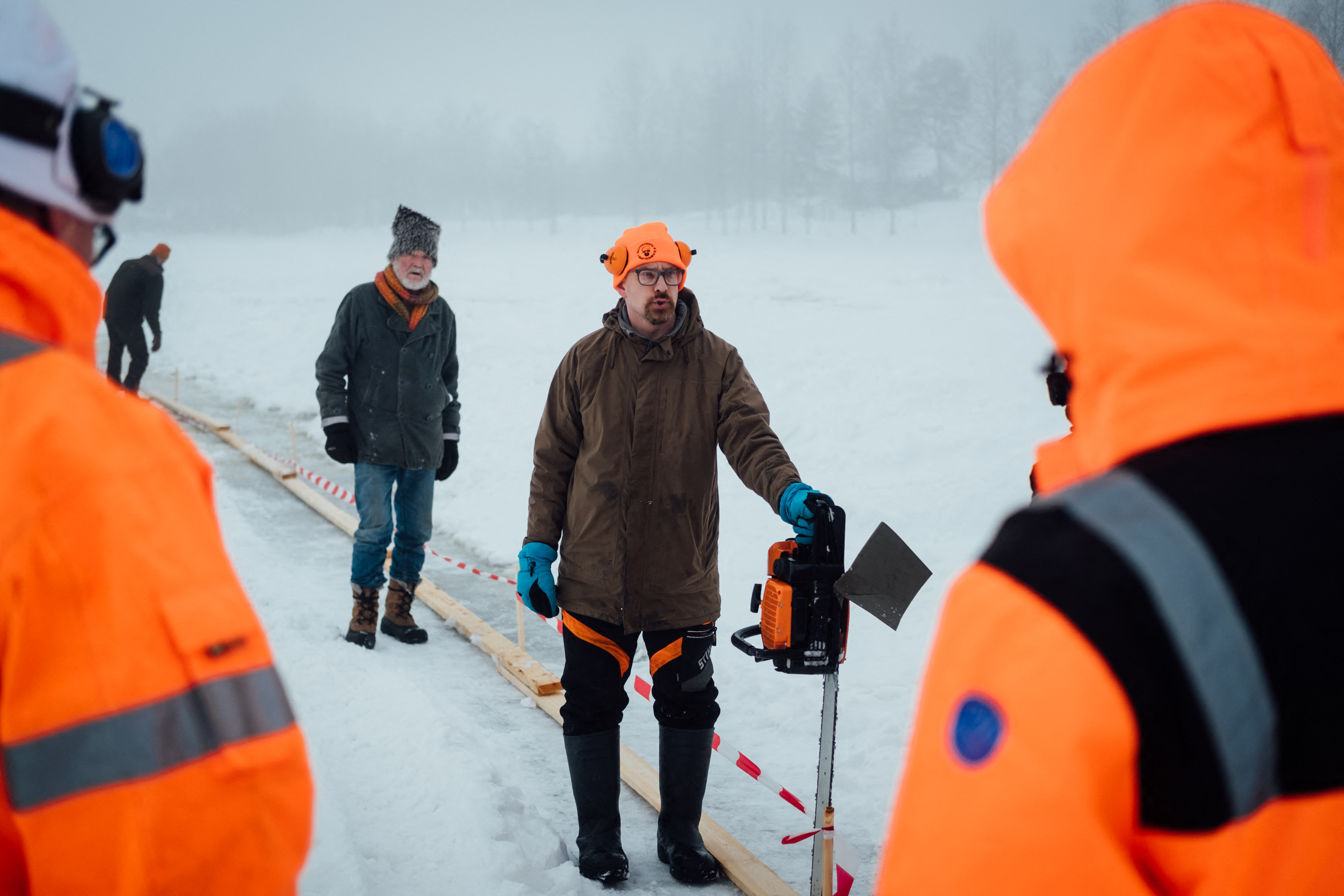 Janne Käpylehto (C) da instrucciones sobre cómo cortar el hielo para realizar el carrusel de hielo. (Alessandro RAMPAZZO / AFP)