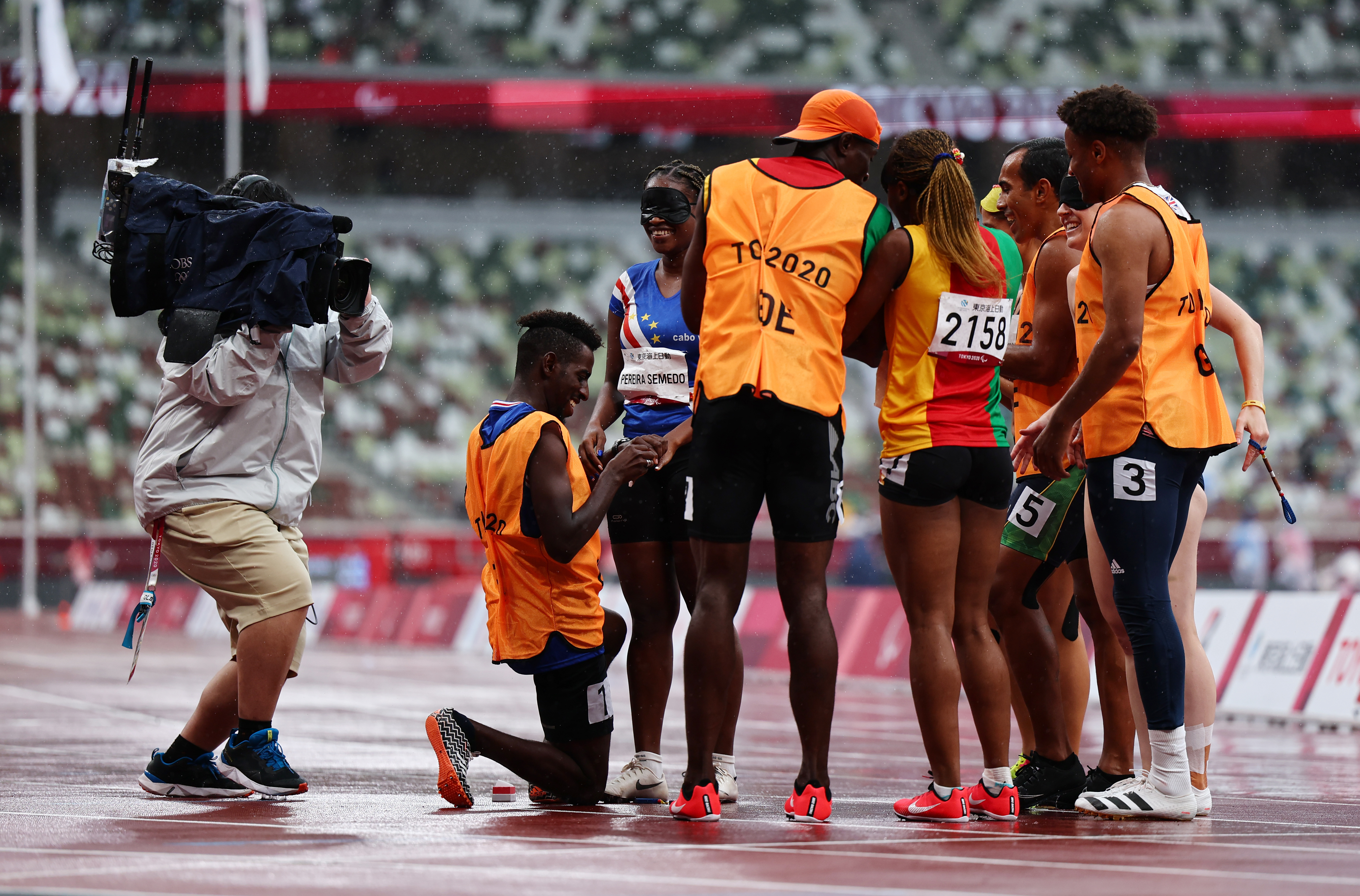 Tokyo 2020 Paralympic Games - Athletics - Women's 200m - T11 Round 1 - Heat 4 - Olympic Stadium, Tokyo, Japan - September 2, 2021. Guide Manuel Antonio Vaz da Veiga on one knee proposes to Keula Nidreia Pereira Semedo of Cape Verde in front of other athletes after competing REUTERS/Athit Perawongmetha