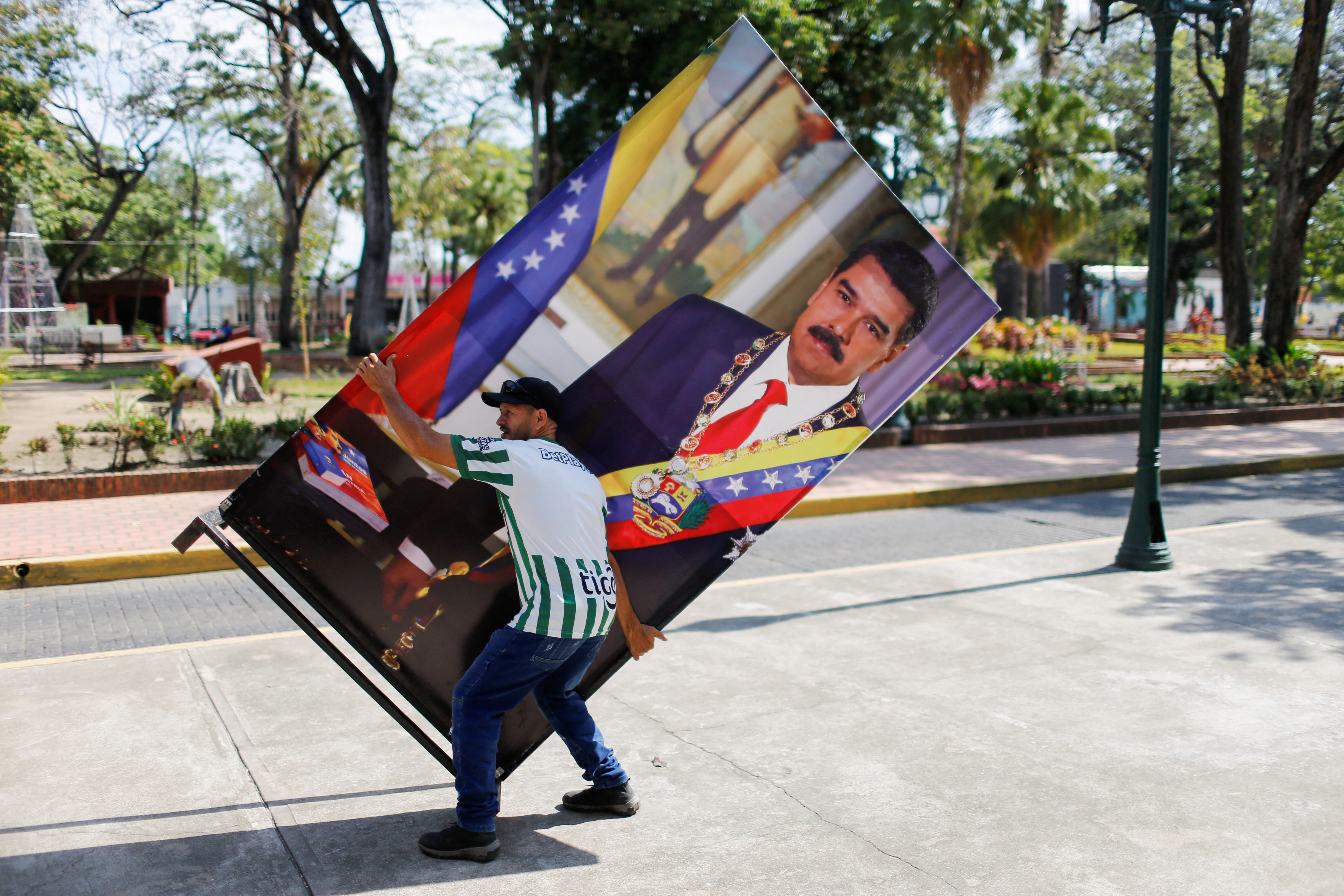Una persona remueve una cartel con la foto de Nicolás Maduro