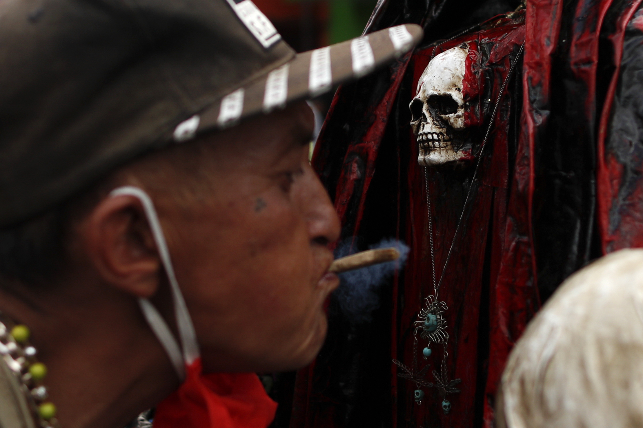 Un hombre sopla humo de marihuana, para limpiarse, sobre el cofre de una Santa Muerte. (Foto: AP / Rebecca Blackwell)
