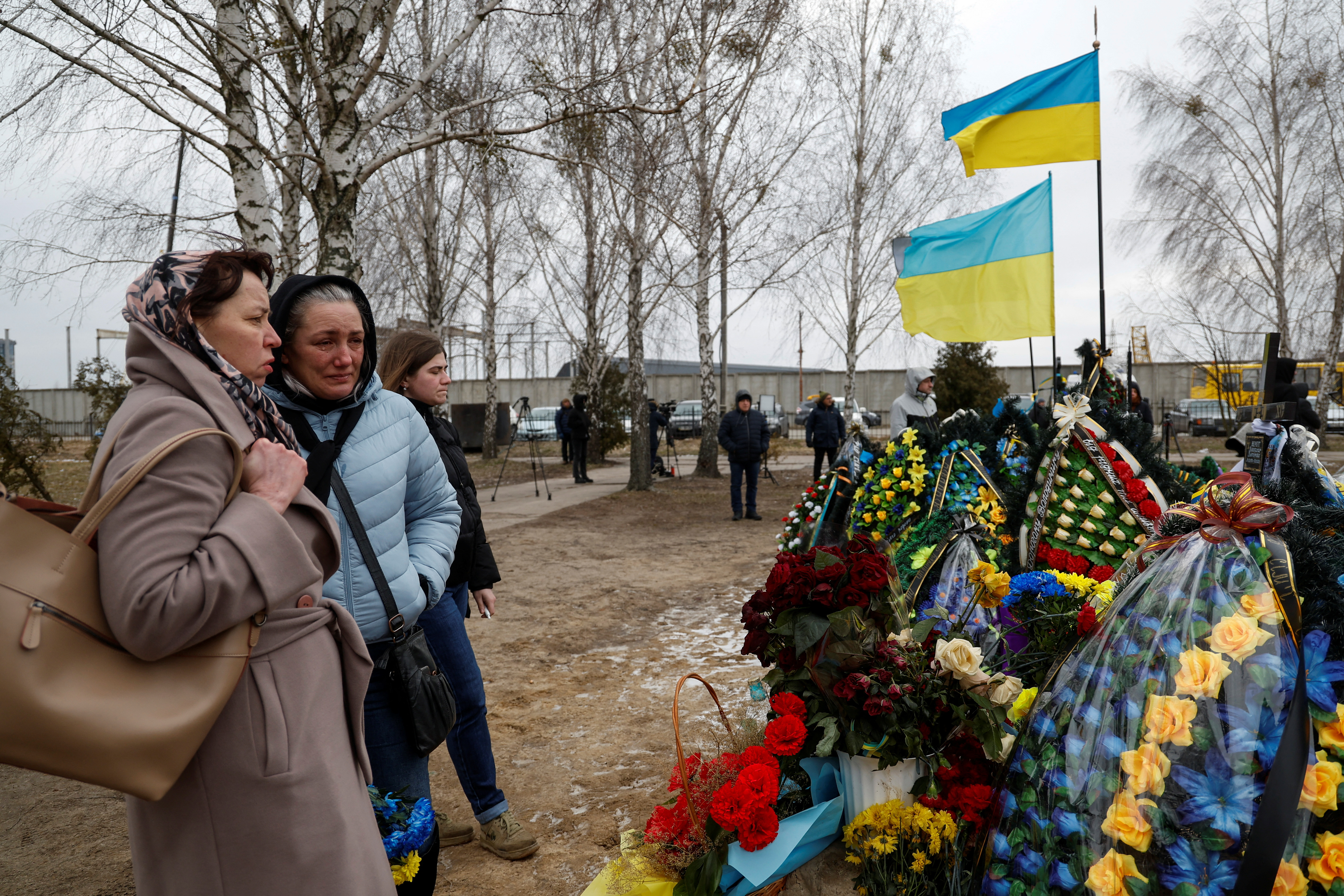 Alla Nechyporenko, de 50 años, habla con su vecina Tetiana Shonia, cuyo hijo Oleksii murió en un combate con tropas rusas cerca de Bakhmut, en un día del primer aniversario del ataque de Rusia a Ucrania, tras visitar la tumba de su marido Ruslan en el cementerio de la ciudad, a las afueras de Kyiv, Ucrania 24 de febrero de 2023. China planea apoyar con armas a Moscú (Reuters)