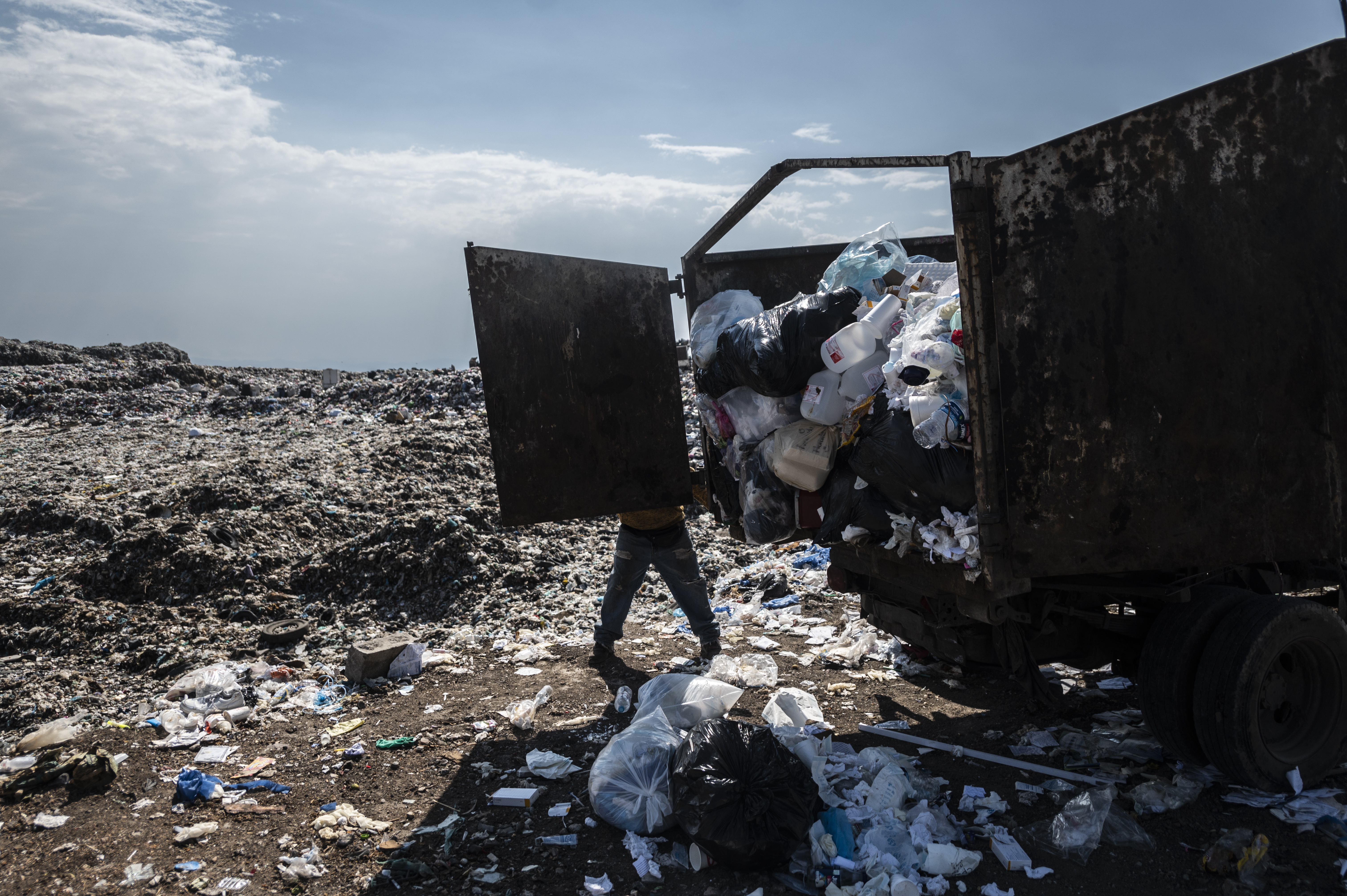 Un recolector de basura descarga desechos médicos en el basurero