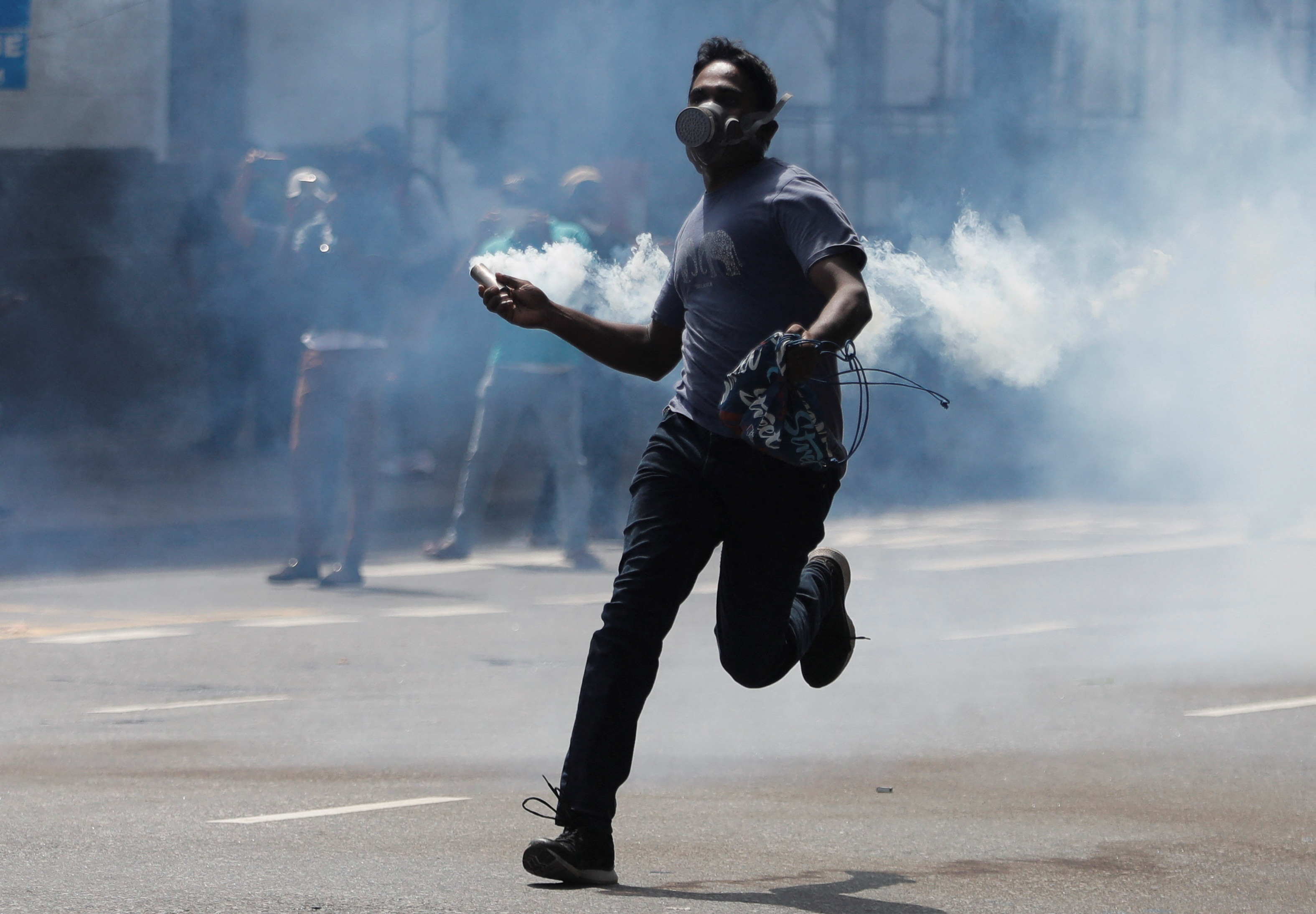 Un manifestante lanza un tubo de gas durante un enfrentamiento con la policía, en las protestas para que renuncie el presidente de Sri Lanka (Gotabaya Rajapaksa REUTERS/Dinuka Liyanawatte)
