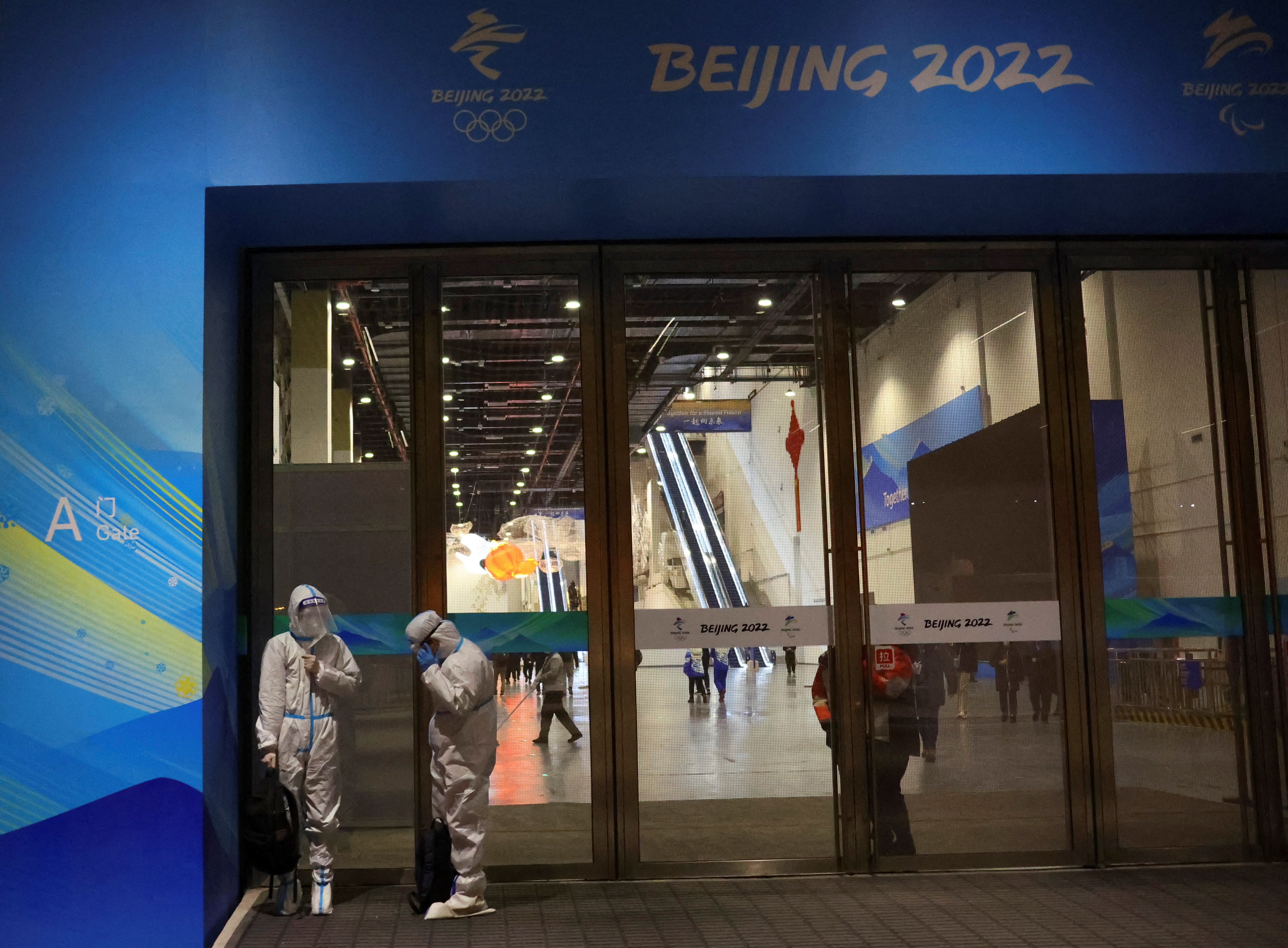 Workers wear  protective suits to protect from coronavirus disease (COVID-19) as they stand outside the Main Press Centre of the Beijing 2022 Winter Olympics ahead of the event in Beijing, China January 19, 2022.    REUTERS/Fabrizio Bensch
